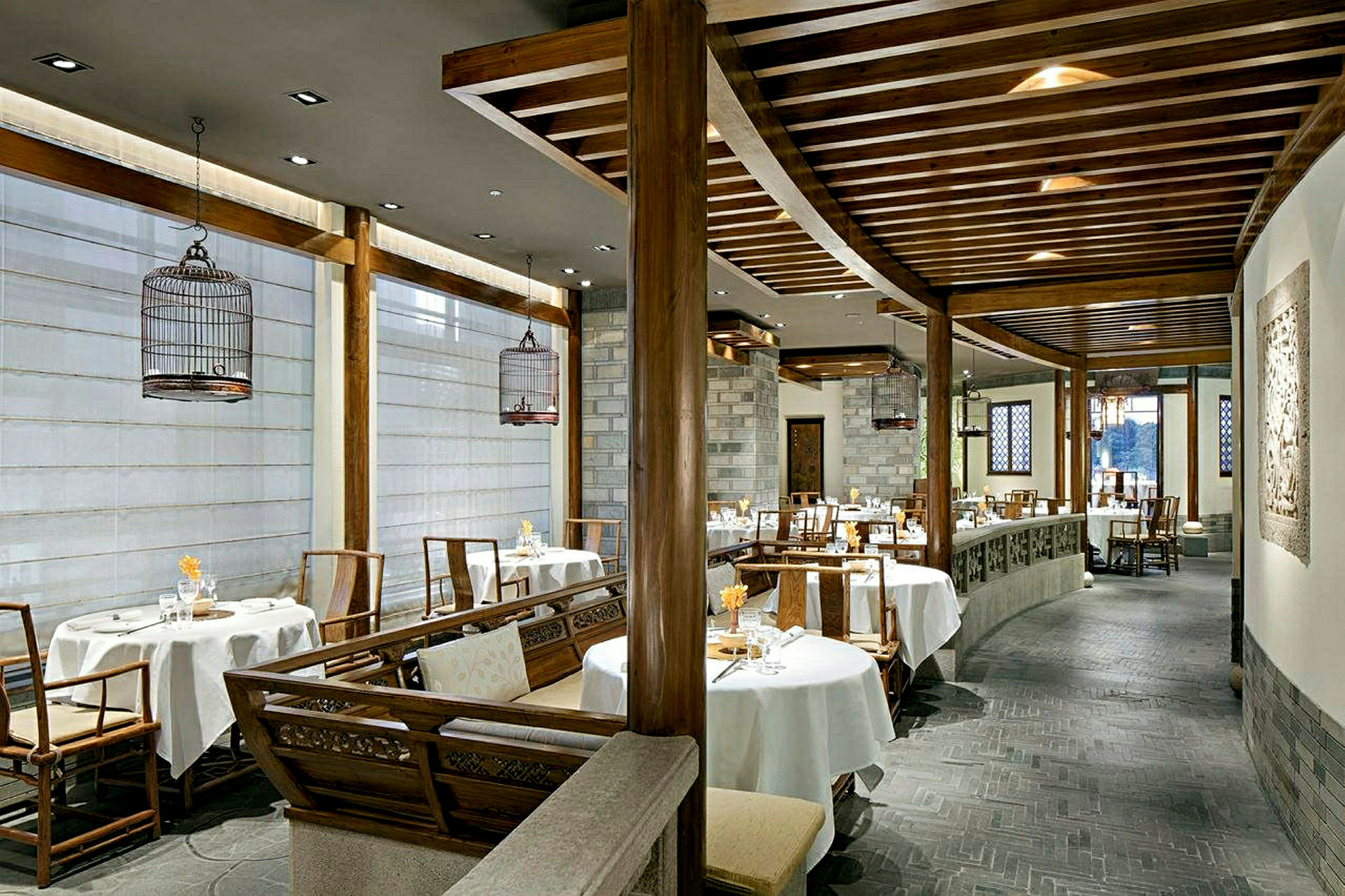 En elegant inredd restaurang med runda bord och stolar, vita dukar och inslag av trä i inredningen. (AI-genererad text)