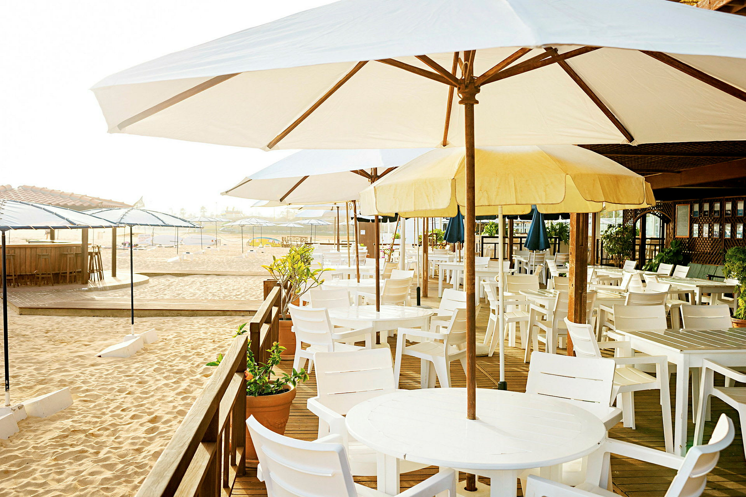En strandbar med parasoller och vita bord och stolar. (AI-genererad text)