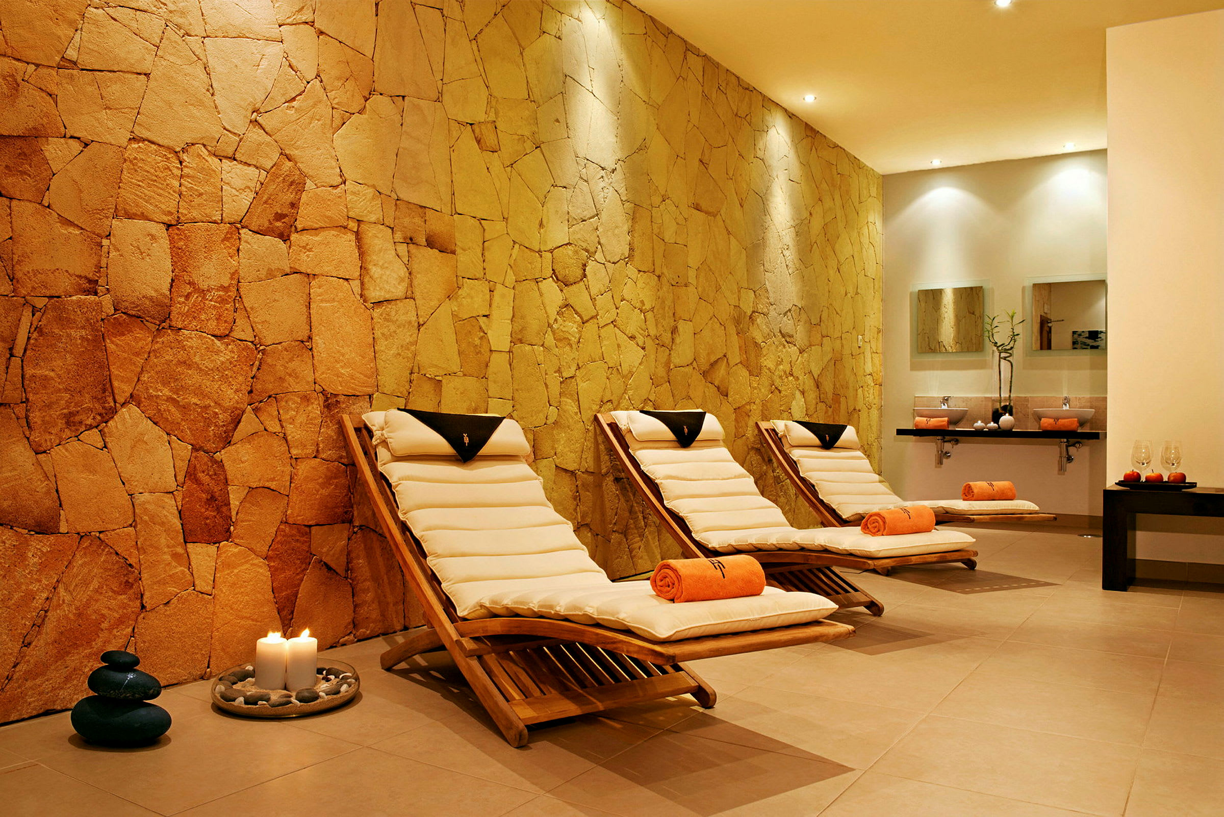Spa-rum med tre solsängar och en vägg av natursten. (AI-genererad text)
