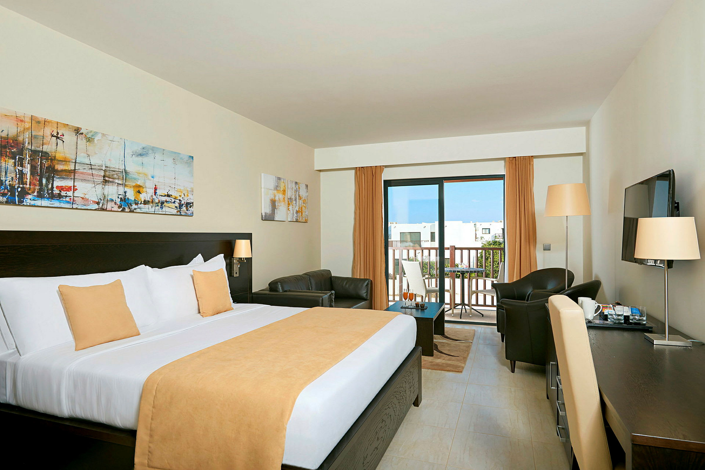 Hotellrum med stor säng, sittgrupp och balkong. (AI-genererad text)