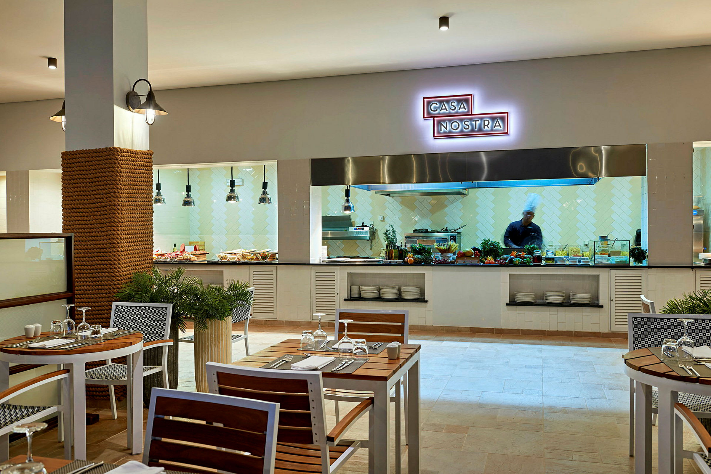 Restaurang med matlagningsdel i bakgrunden och dukade bord i förgrunden. (AI-genererad text)