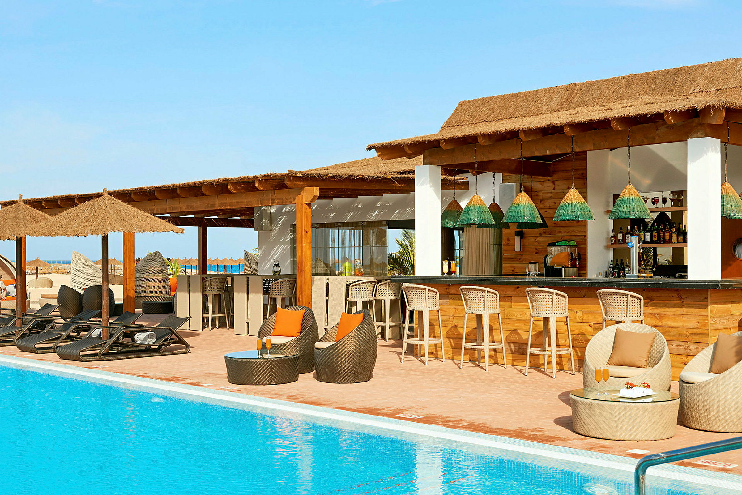 Bild på en pool med solstolar och en strandbar med sittplatser. (AI-genererad text)