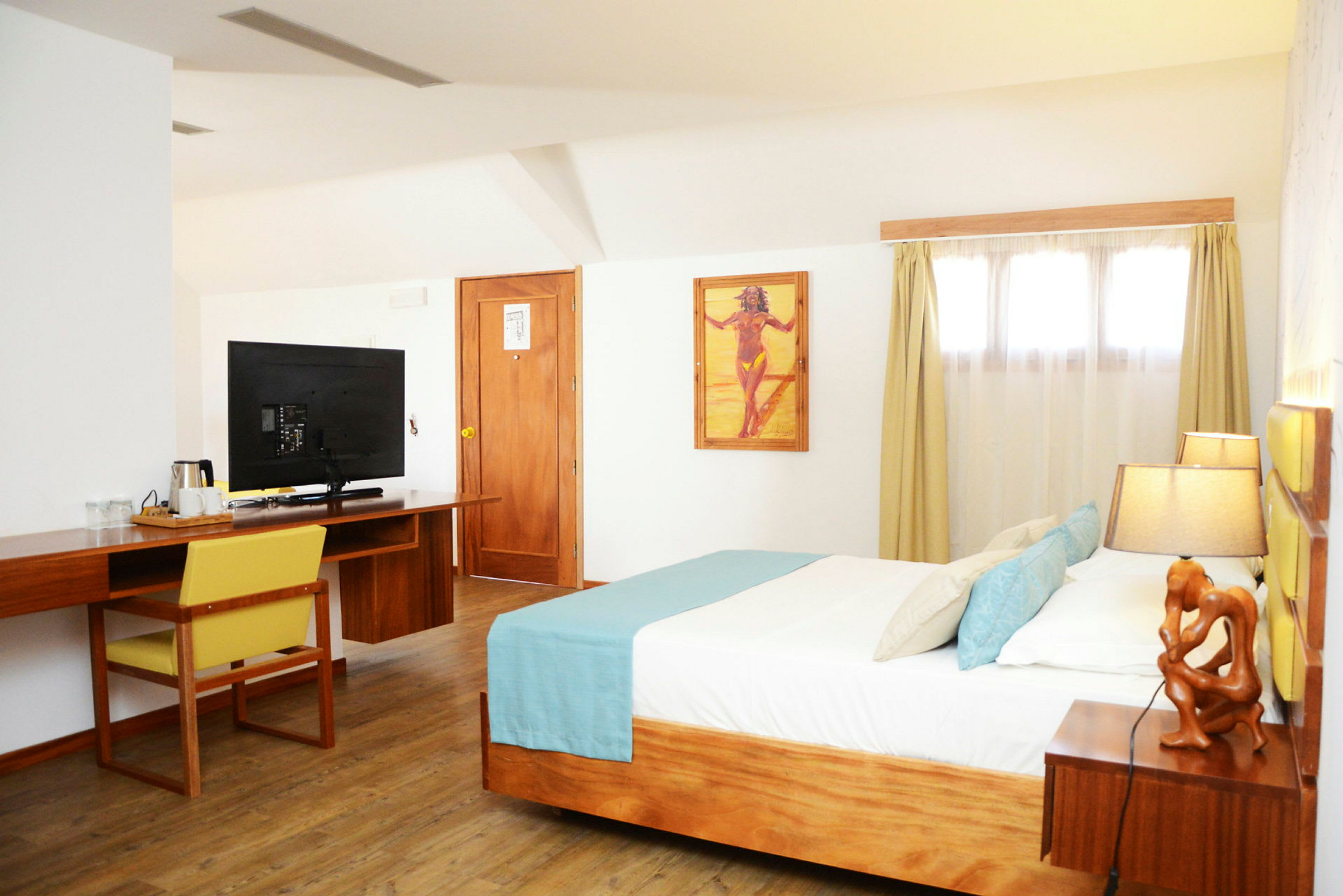 Ett hotellrum med en säng, skrivbord, TV och dekorationer. (AI-genererad text)