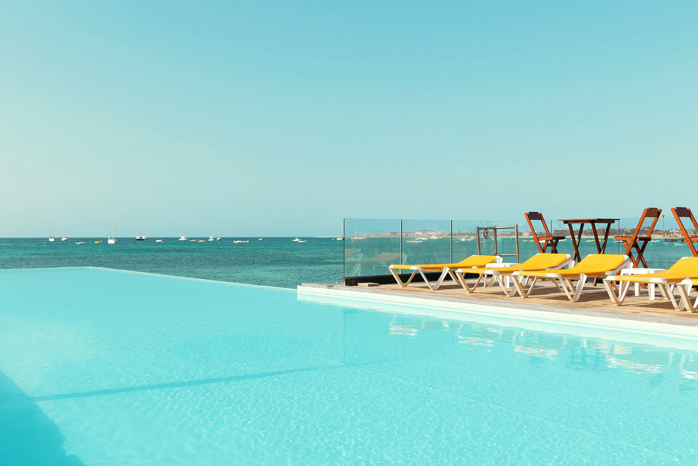 Pool med utsikt över havet och solstolar vid sidan. (AI-genererad text)