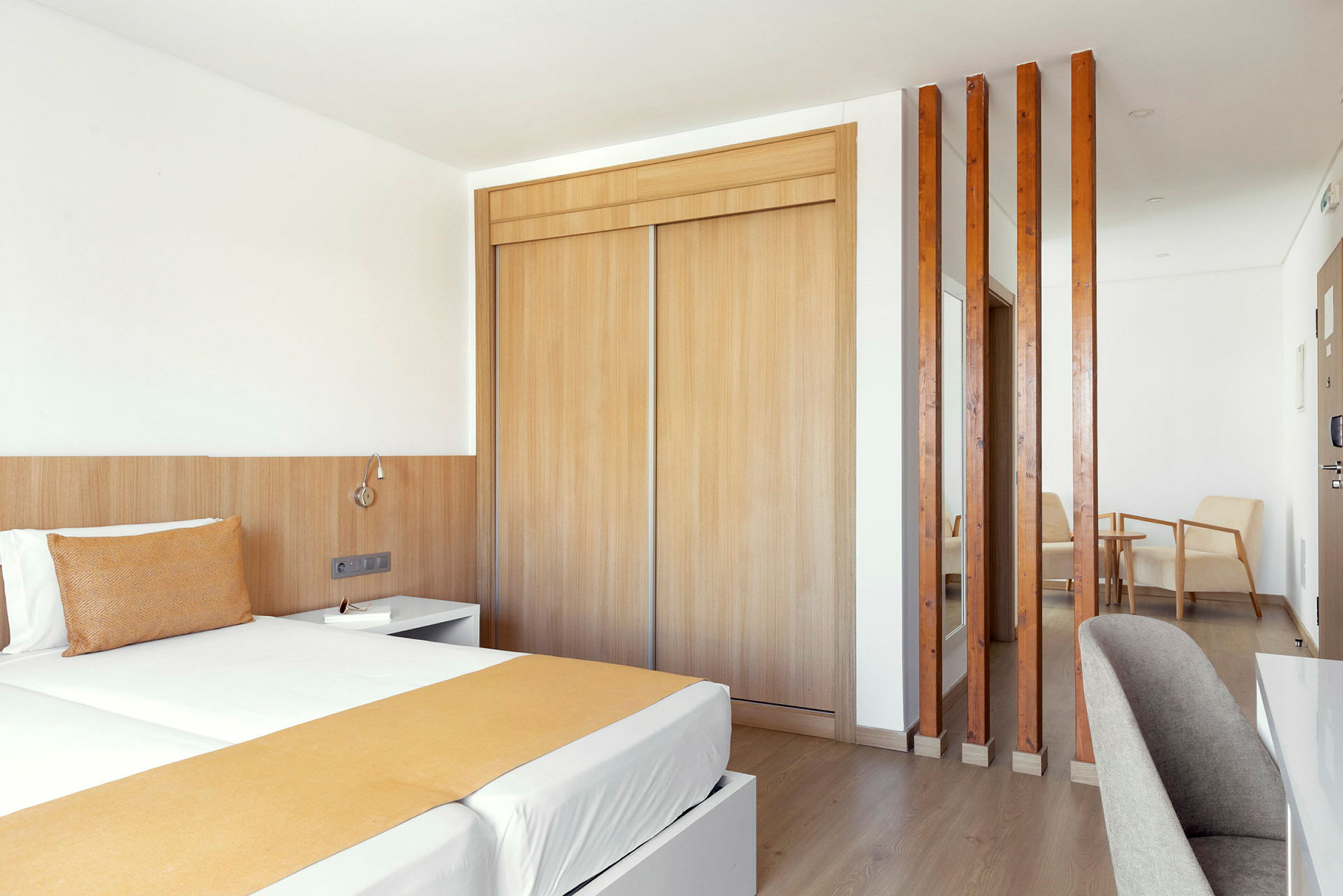 Ett hotellrum med en dubbelsäng, trämöbler och en sittgrupp. (AI-genererad text)