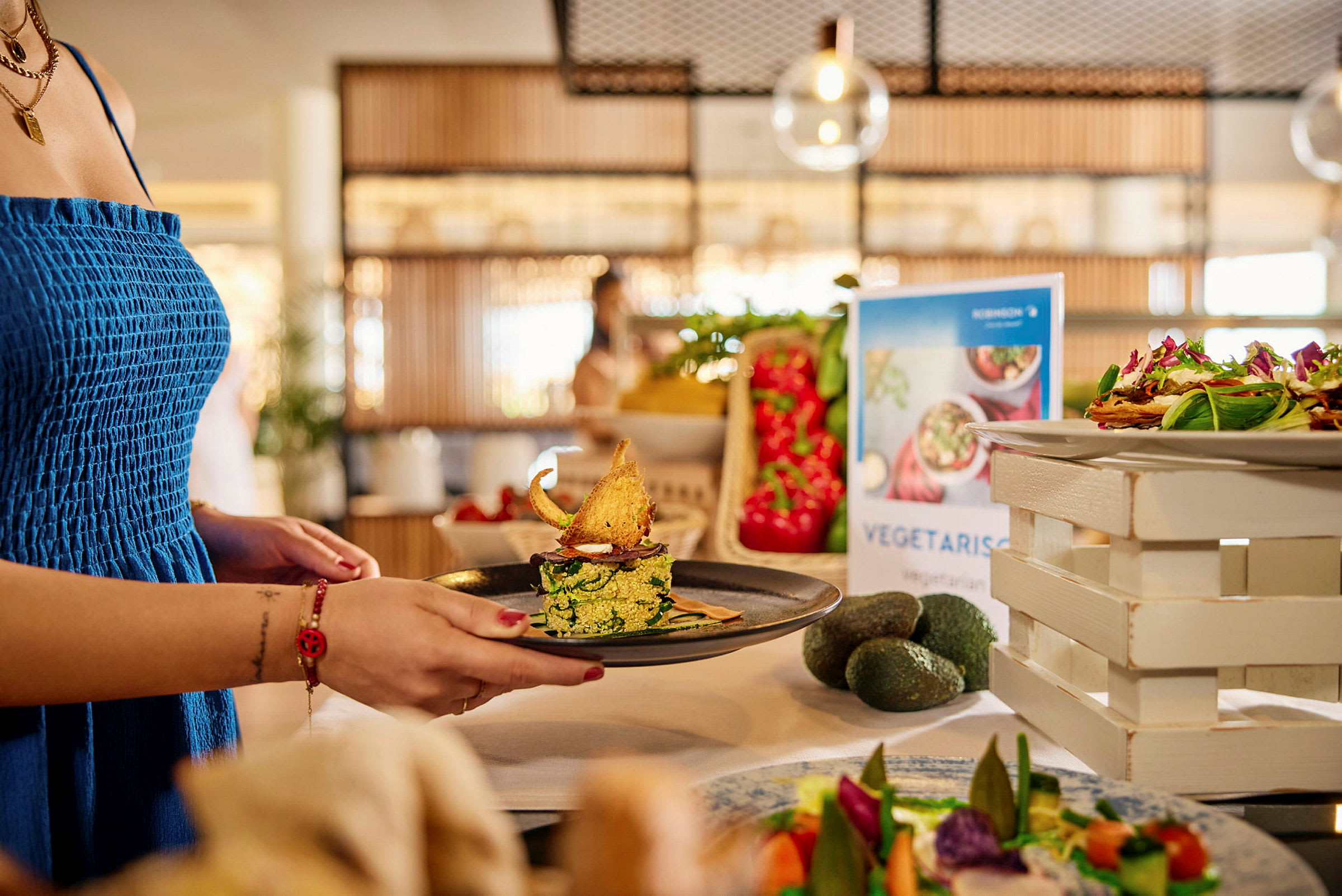 En person håller en tallrik med en vegetarisk rätt på en buffé. (AI-genererad text)