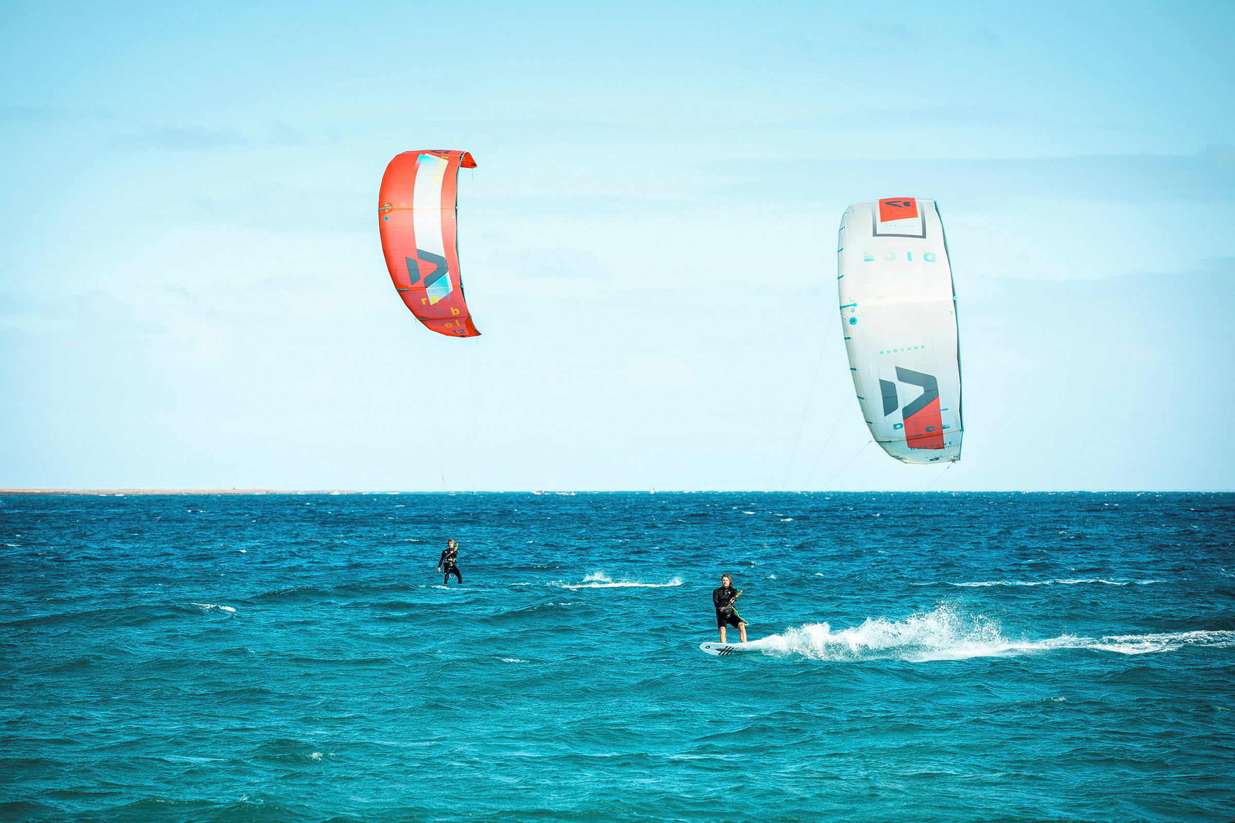 Två personer åker kitesurfing på havet med färgglada drakar. (AI-genererad text)