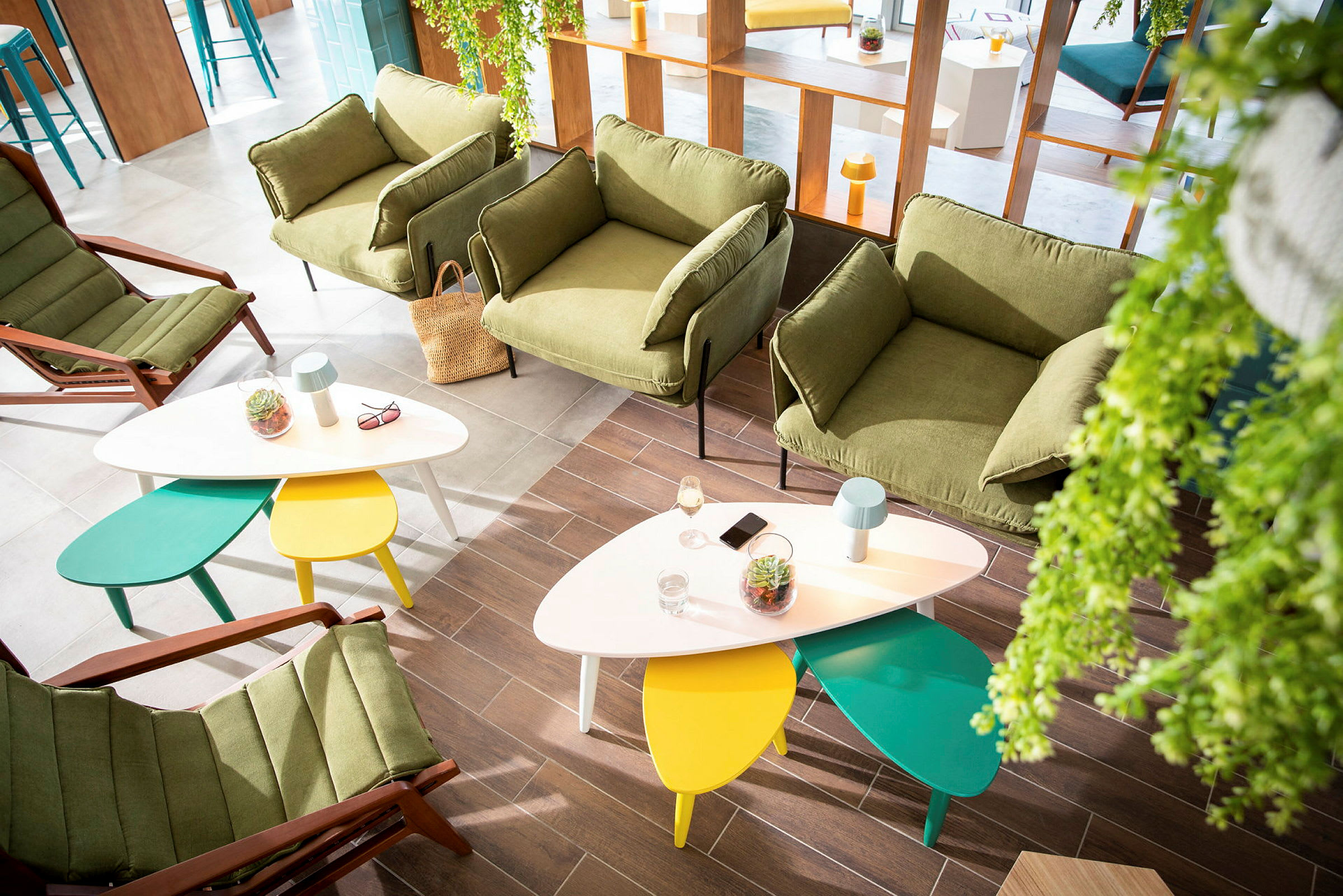 Modern lounge med gröna fåtöljer och färgglada bord. (AI-genererad text)