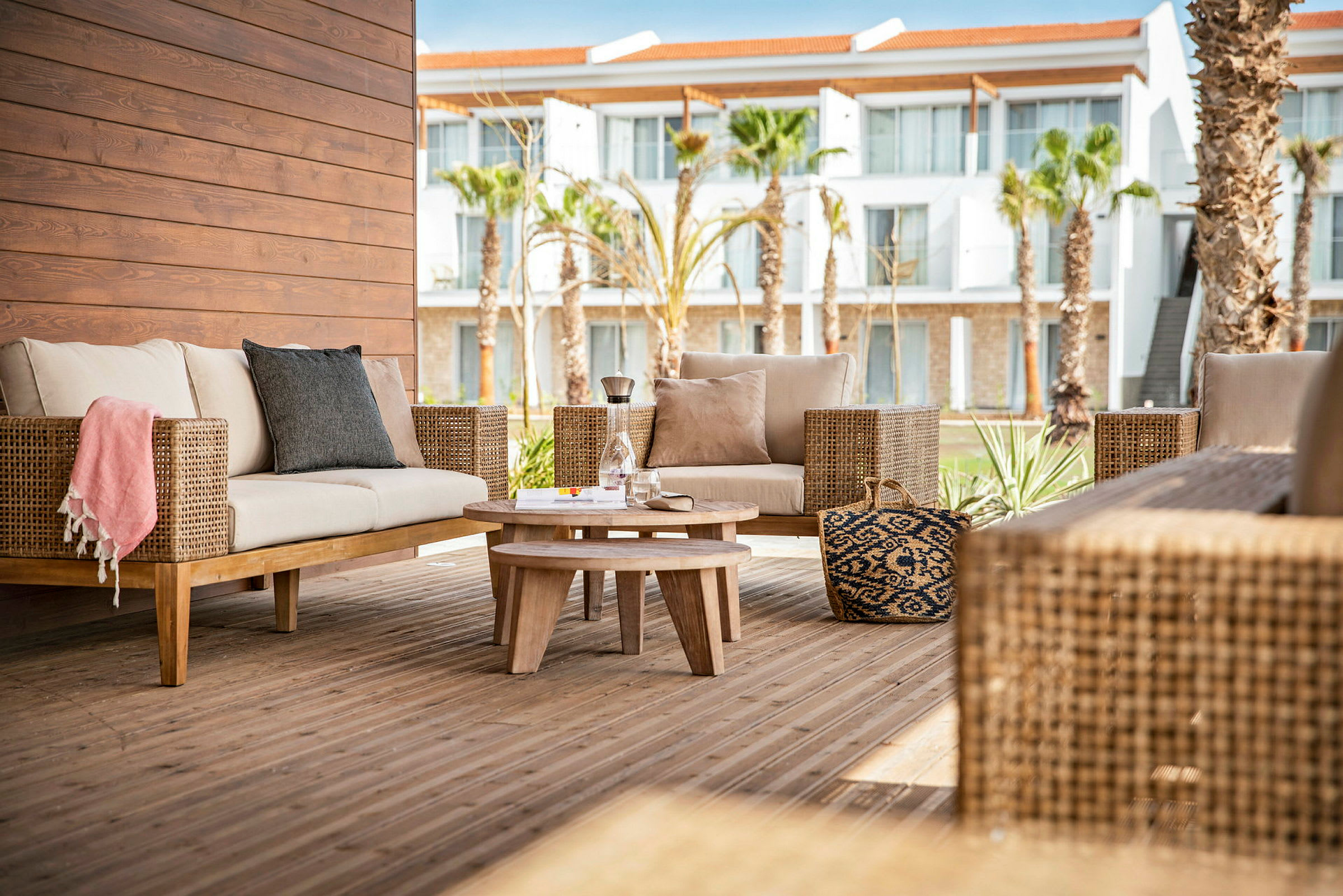 Utomhus loungeområde med rottingmöbler och ett träbord på en terrass. (AI-genererad text)