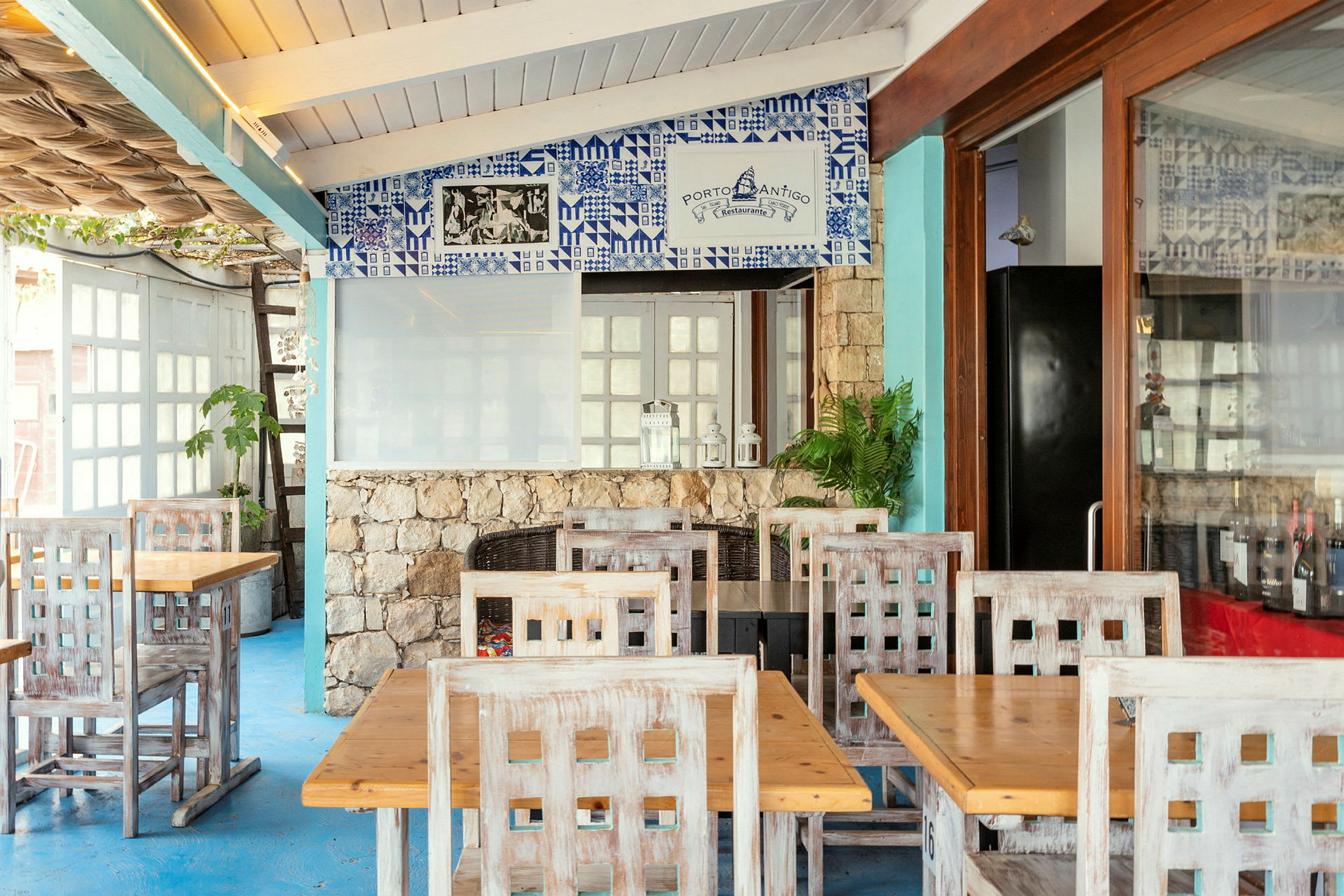 Restaurang med träbord och stolar samt dekorerad vägg med blått kakel. (AI-genererad text)