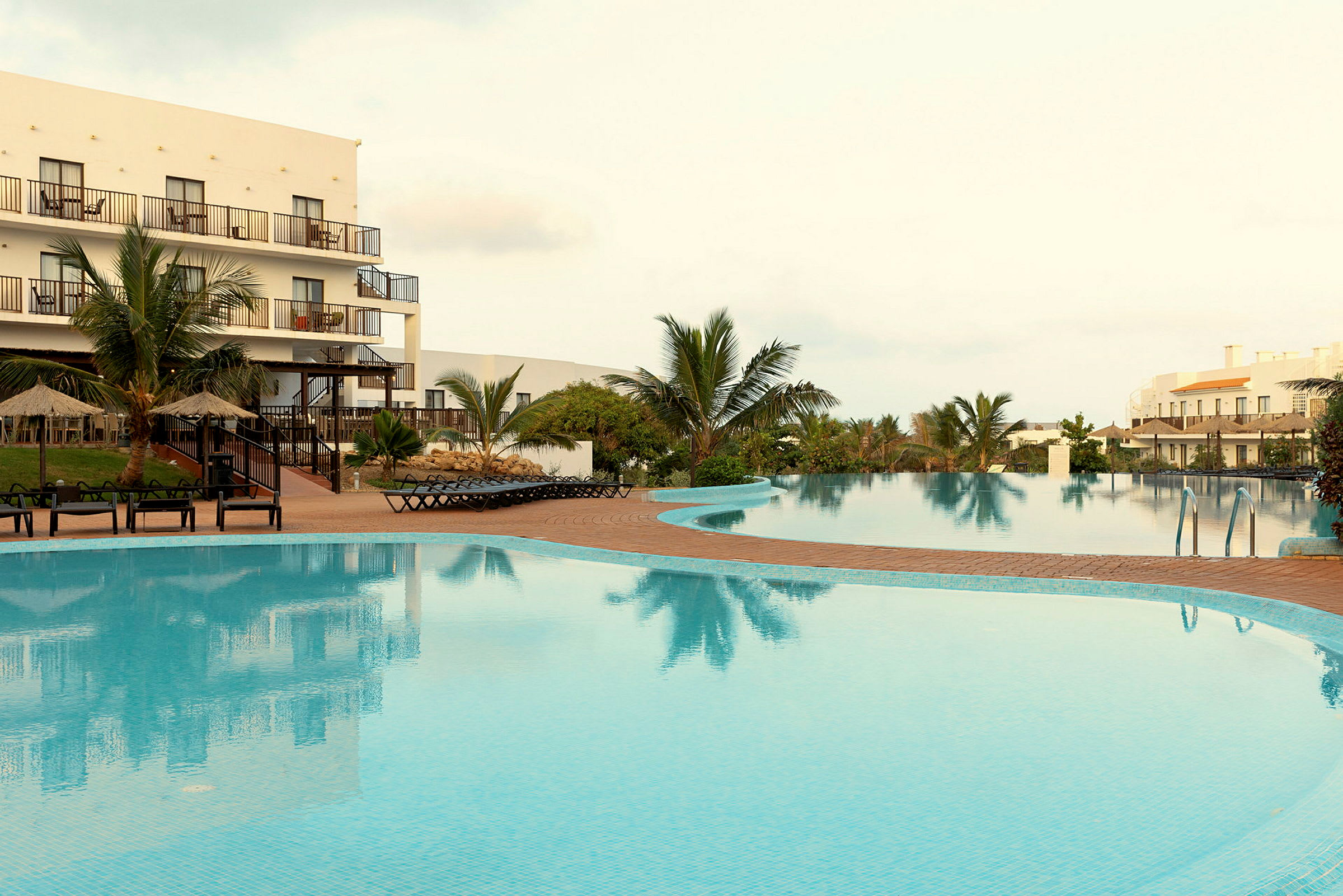 Bild av en utomhuspool vid ett hotell med palmer och solstolar. (AI-genererad text)