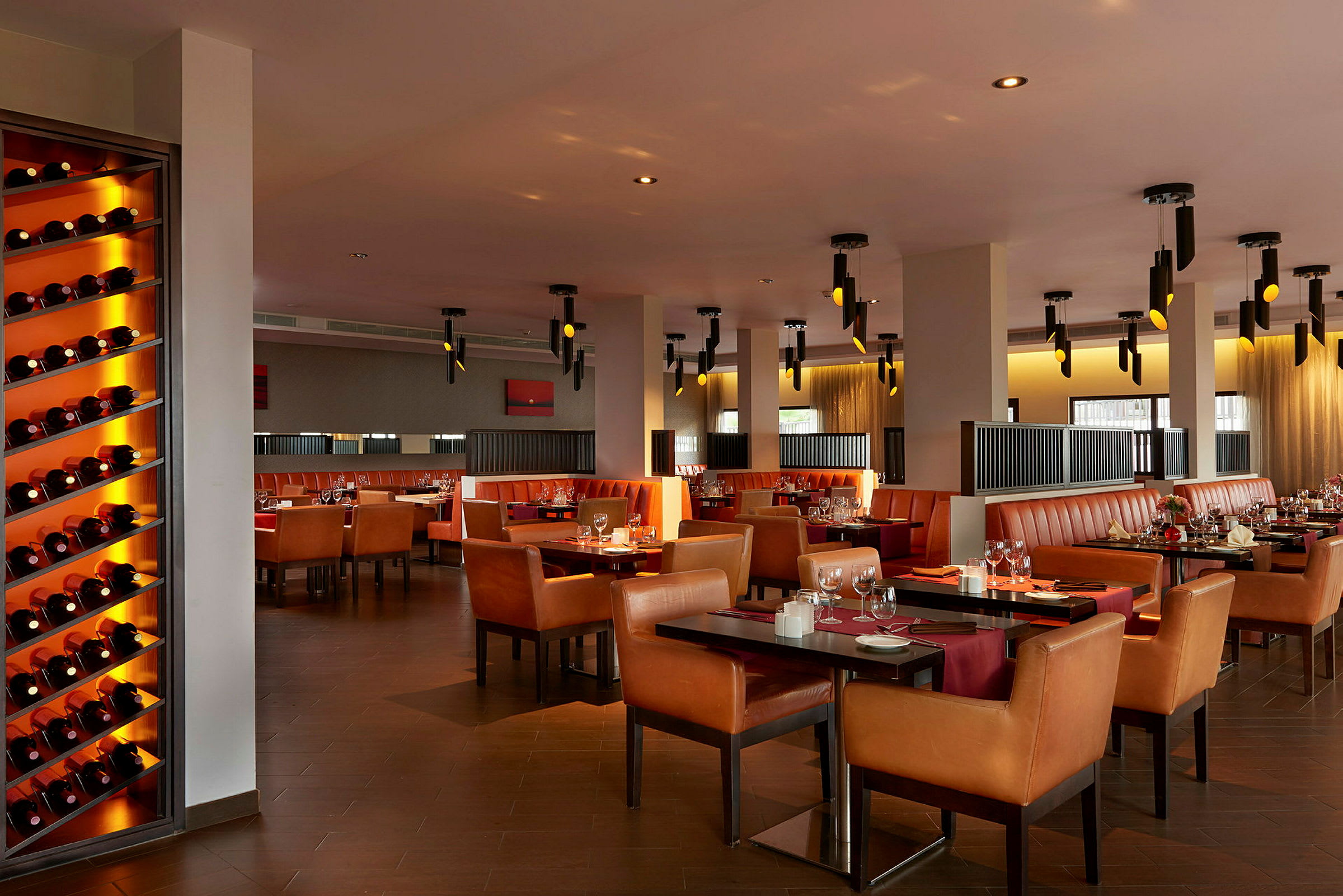 En restaurang med flera bord, stolar och vinflaskor på en hylla. (AI-genererad text)