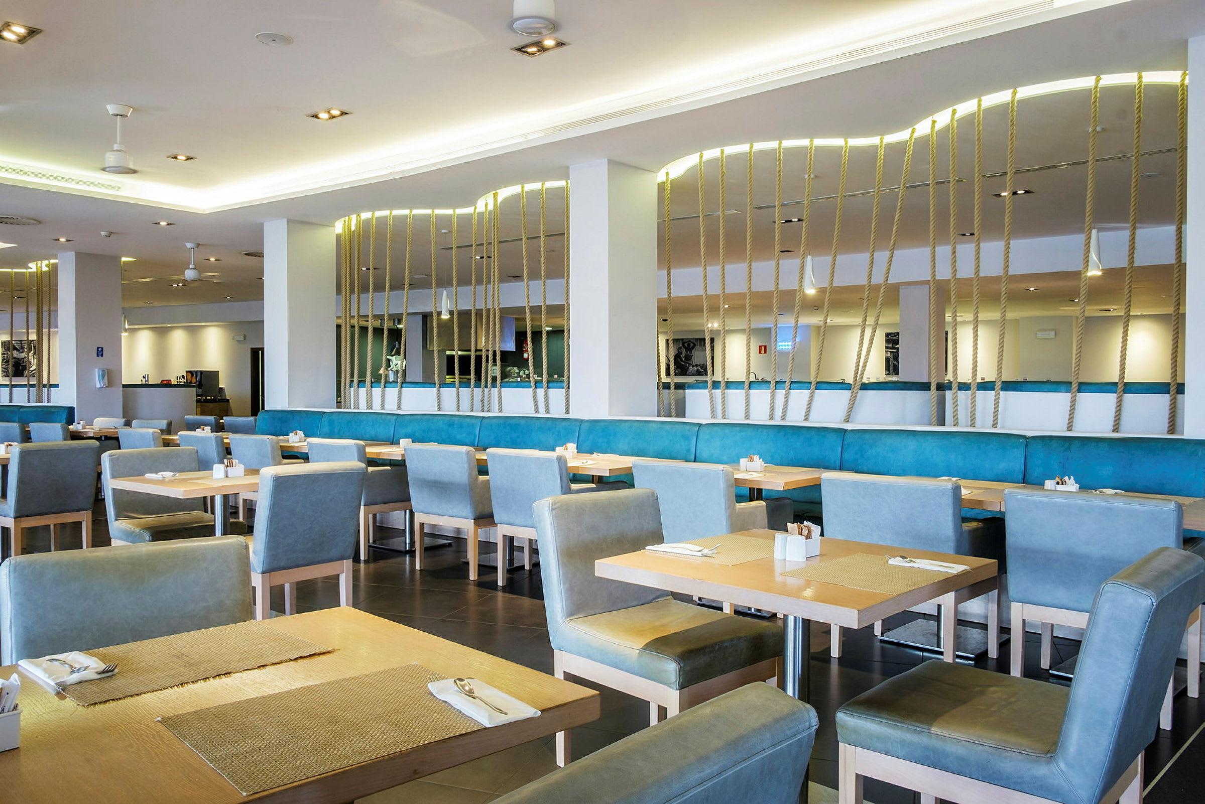 Interiör av en restaurang med bord och blå stolar. (AI-genererad text)