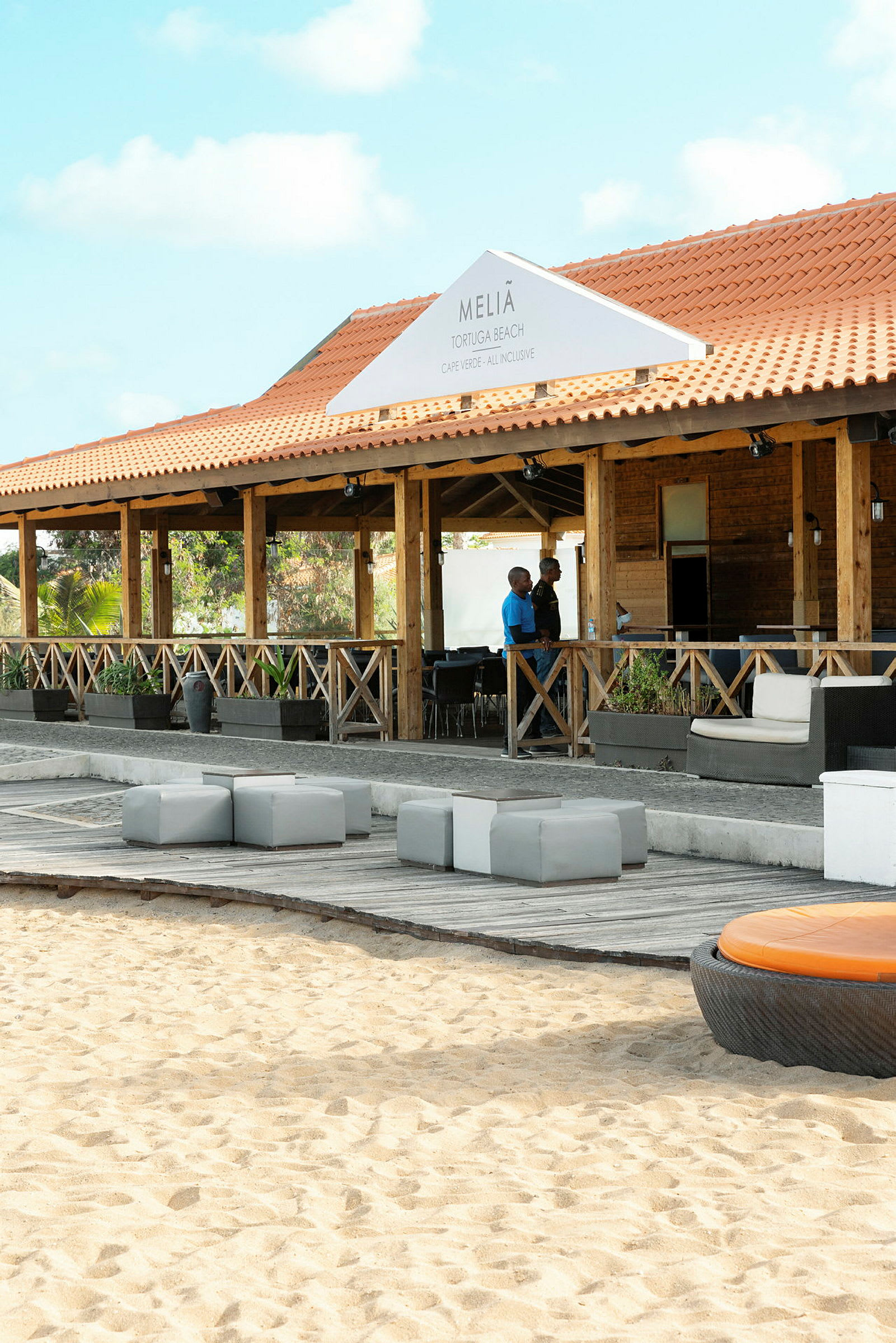 Restaurangbyggnad med uteservering nära sandstrand. (AI-genererad text)