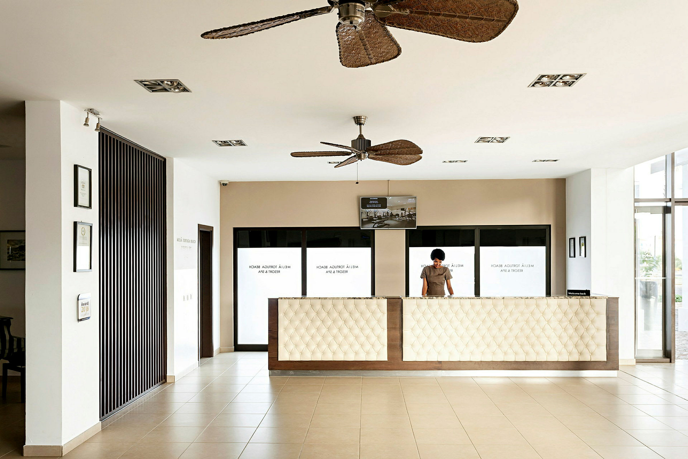Reception i en modern byggnad med vita väggar, stora fönster och takfläktar. (AI-genererad text)