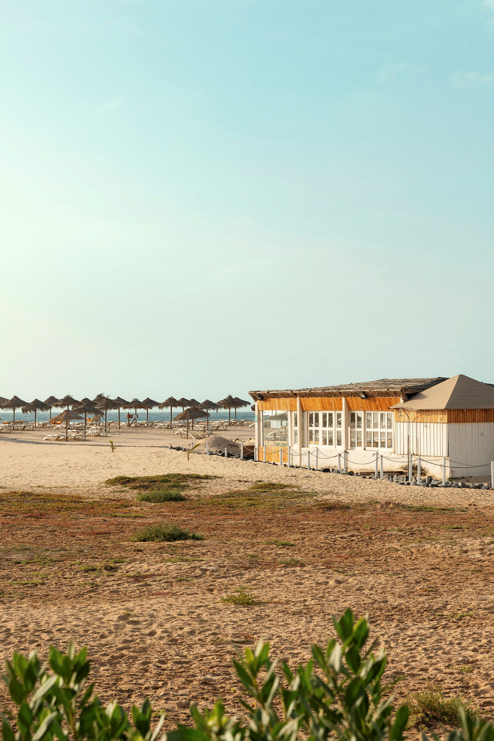 Strand med parasoller och en träbyggnad. (AI-genererad text)