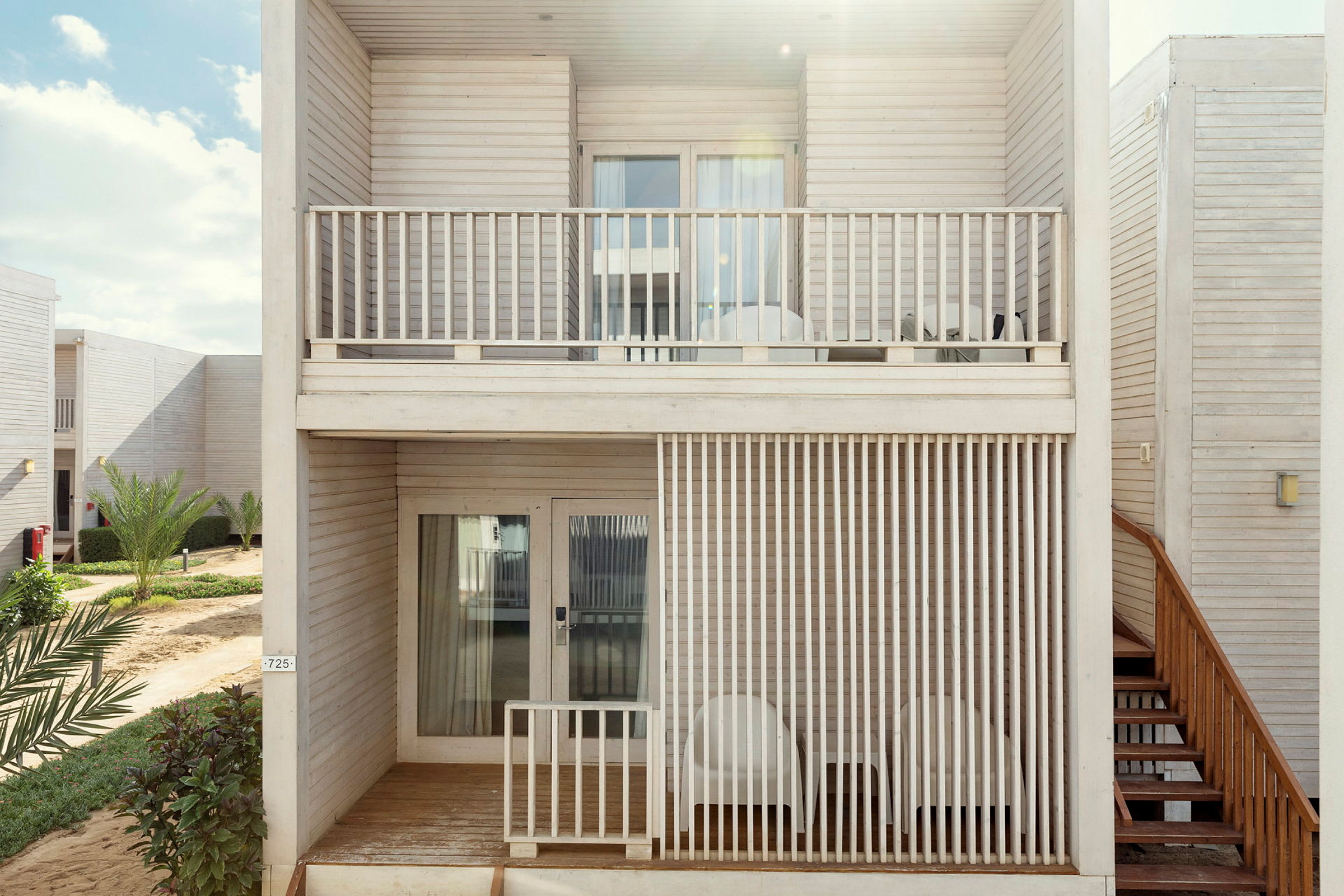 Två våningar med lagenhetsbalkonger i trädesign, omgivna av grönska. (AI-genererad text)