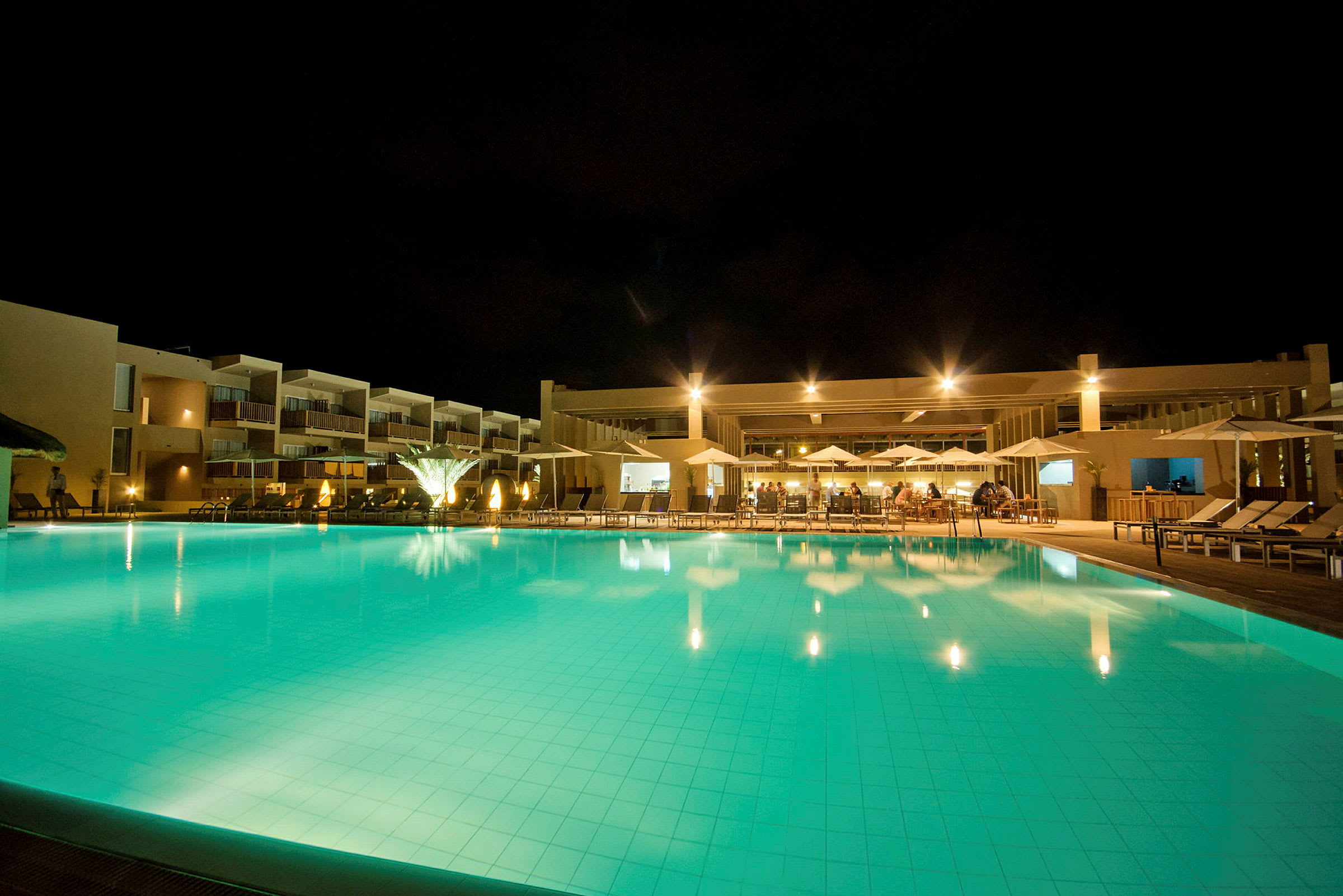 Hotellpoolen och byggnaden lyst upp på kvällen. (AI-genererad text)