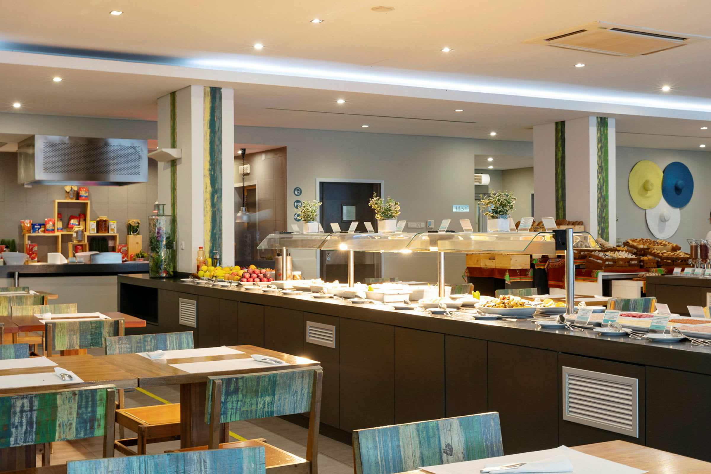 Interiör av en bufférestaurang med serveringsbord fyllda av olika rätter och frukter. (AI-genererad text)