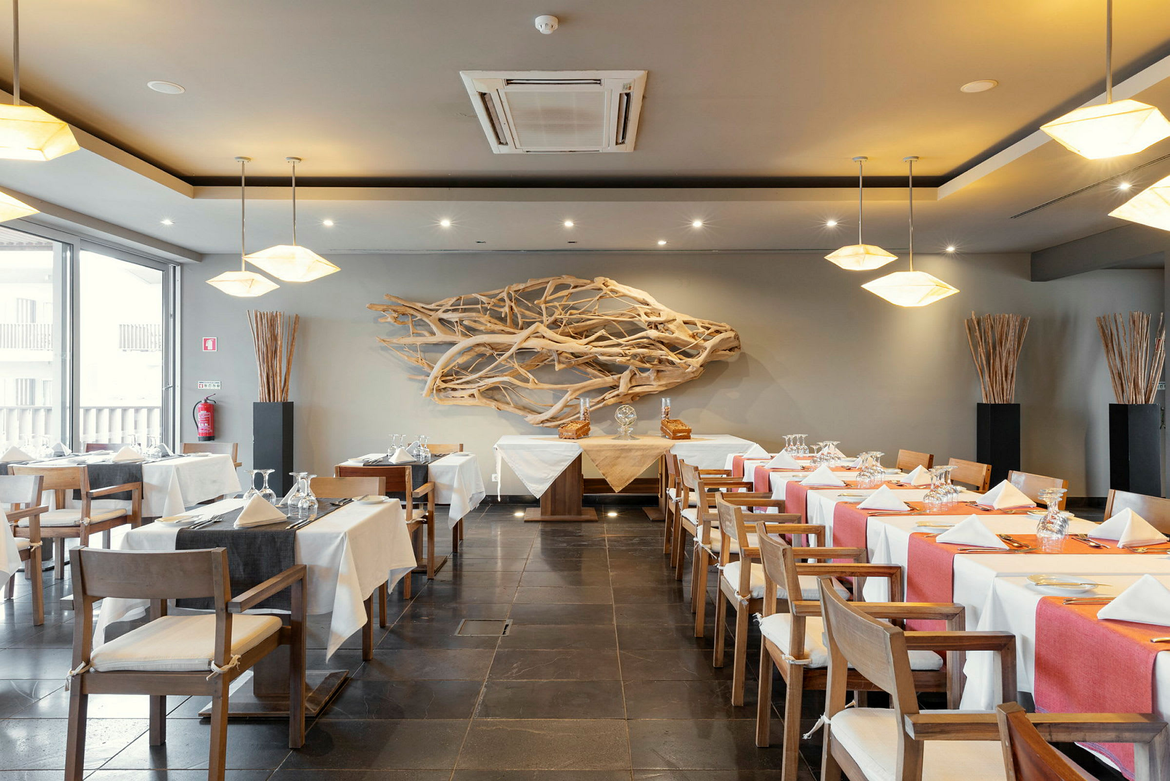 En restaurang med dukade bord, dekorerade stolar, och träkonst på väggen. (AI-genererad text)
