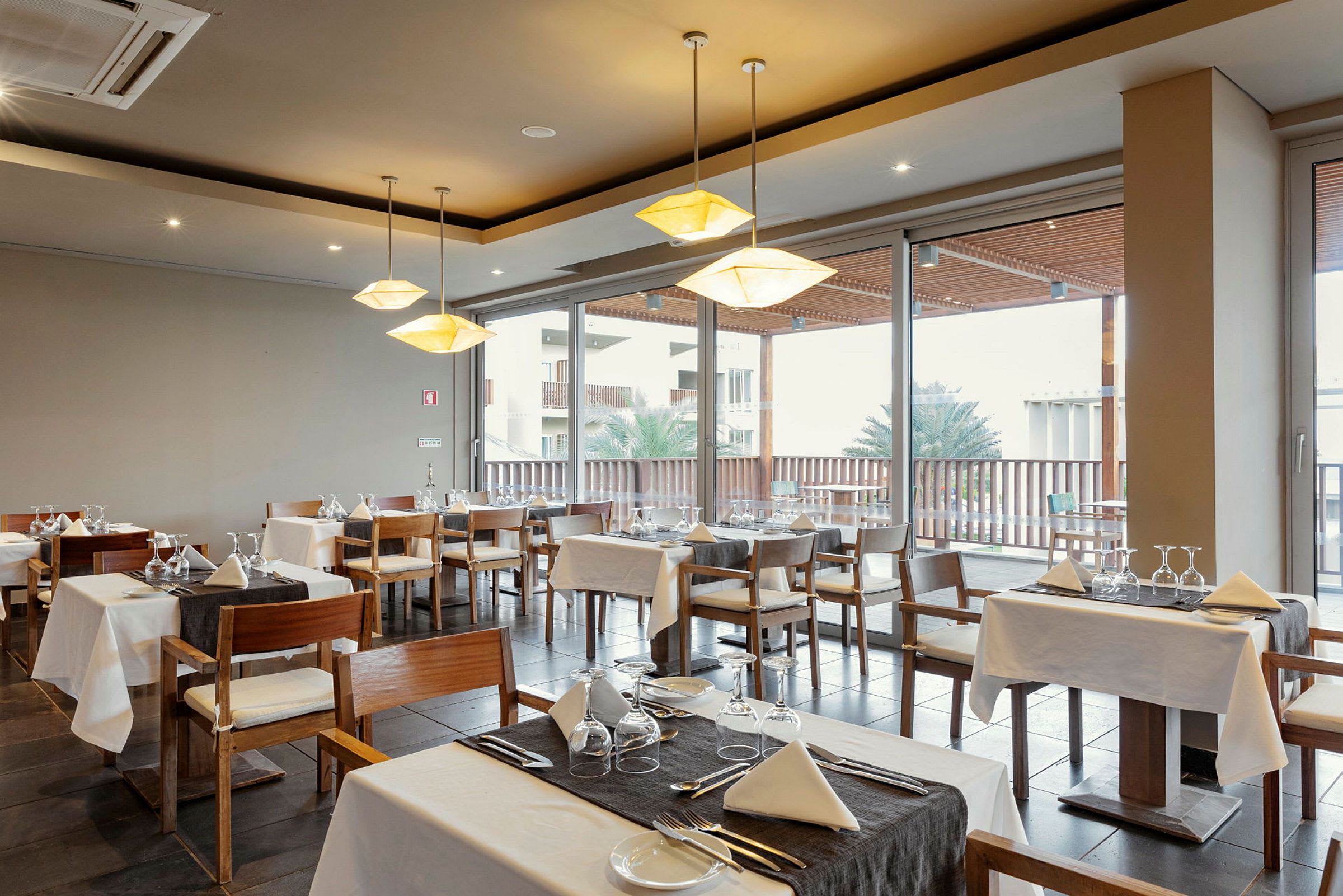 Restaurang med dukade bord och stolar nära stora fönster. (AI-genererad text)