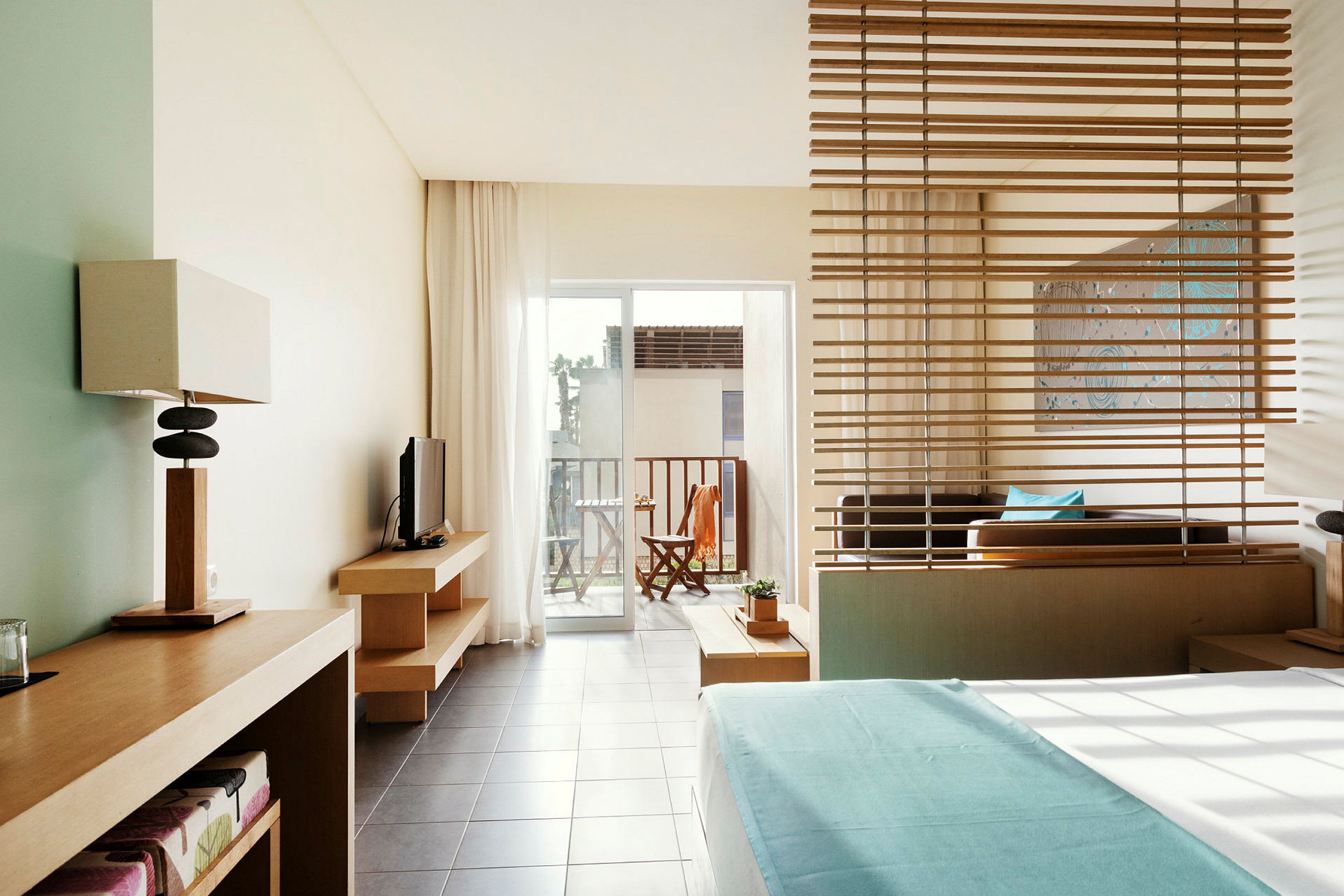 Ett hotellrum med modern inredning och utsikt mot en balkong med utemöbler. (AI-genererad text)