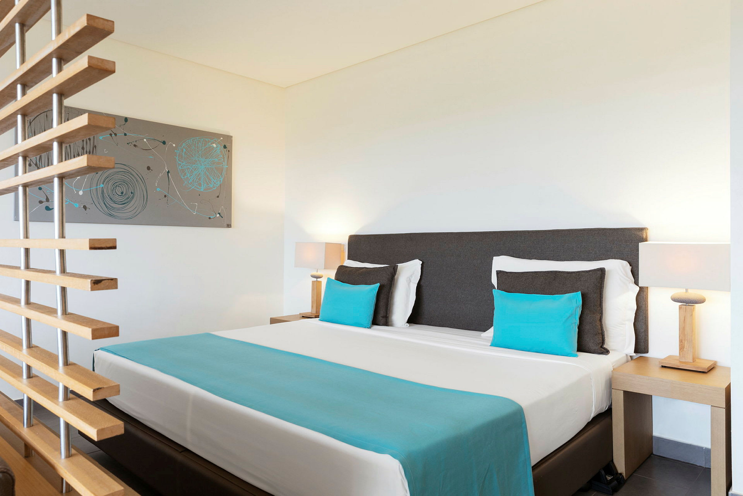 Ett hotellrum med en säng och blåa kuddar samt en väggdekoration. (AI-genererad text)