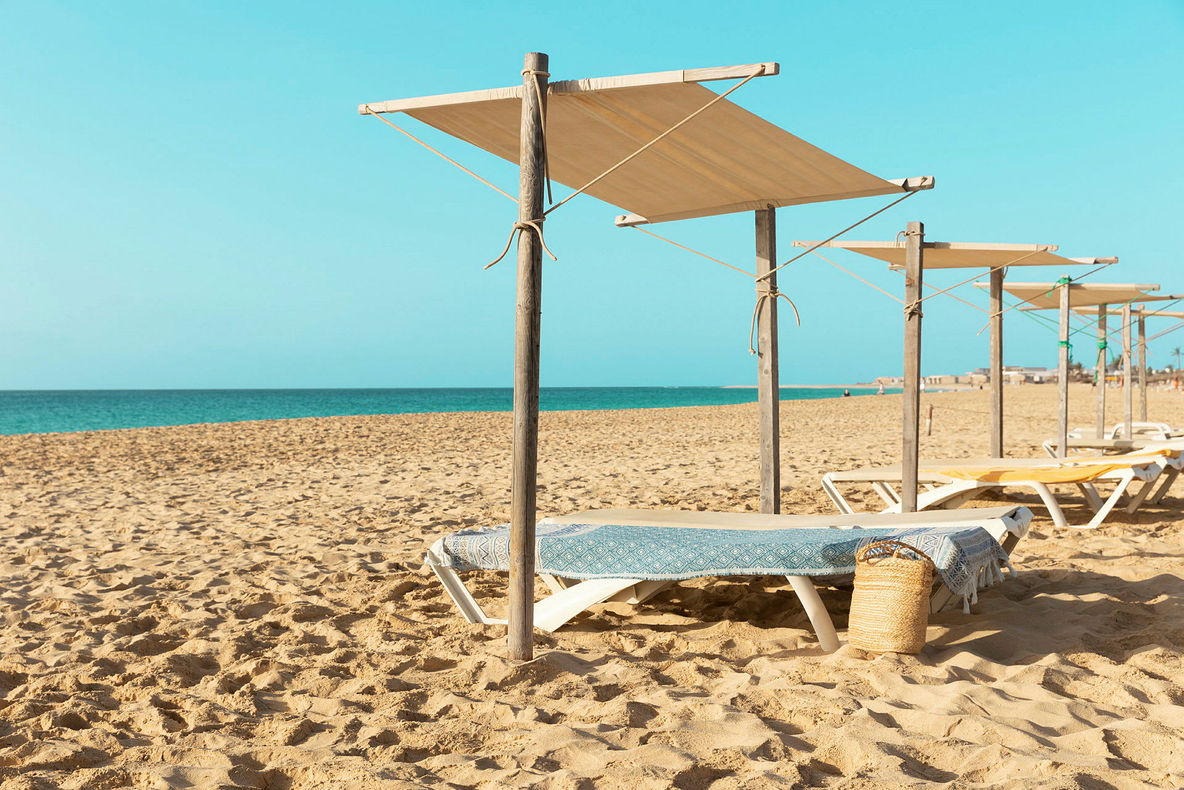 Solstolar med skuggande parasoller på en sandstrand med havet i bakgrunden. (AI-genererad text)