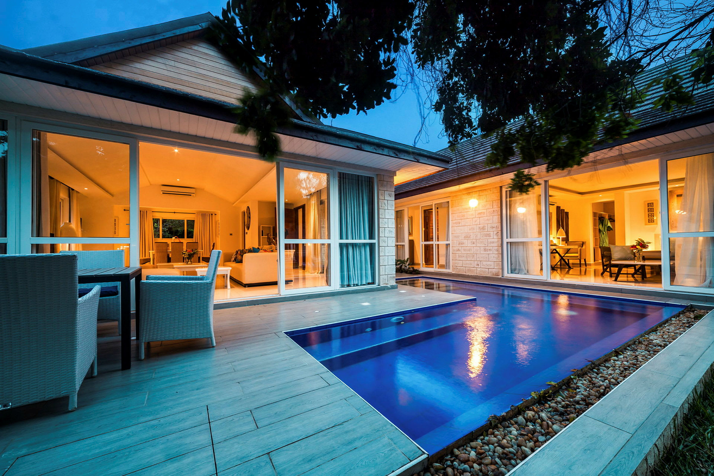En villa med stora glasfönster och en pool i förgrunden. (AI-genererad text)