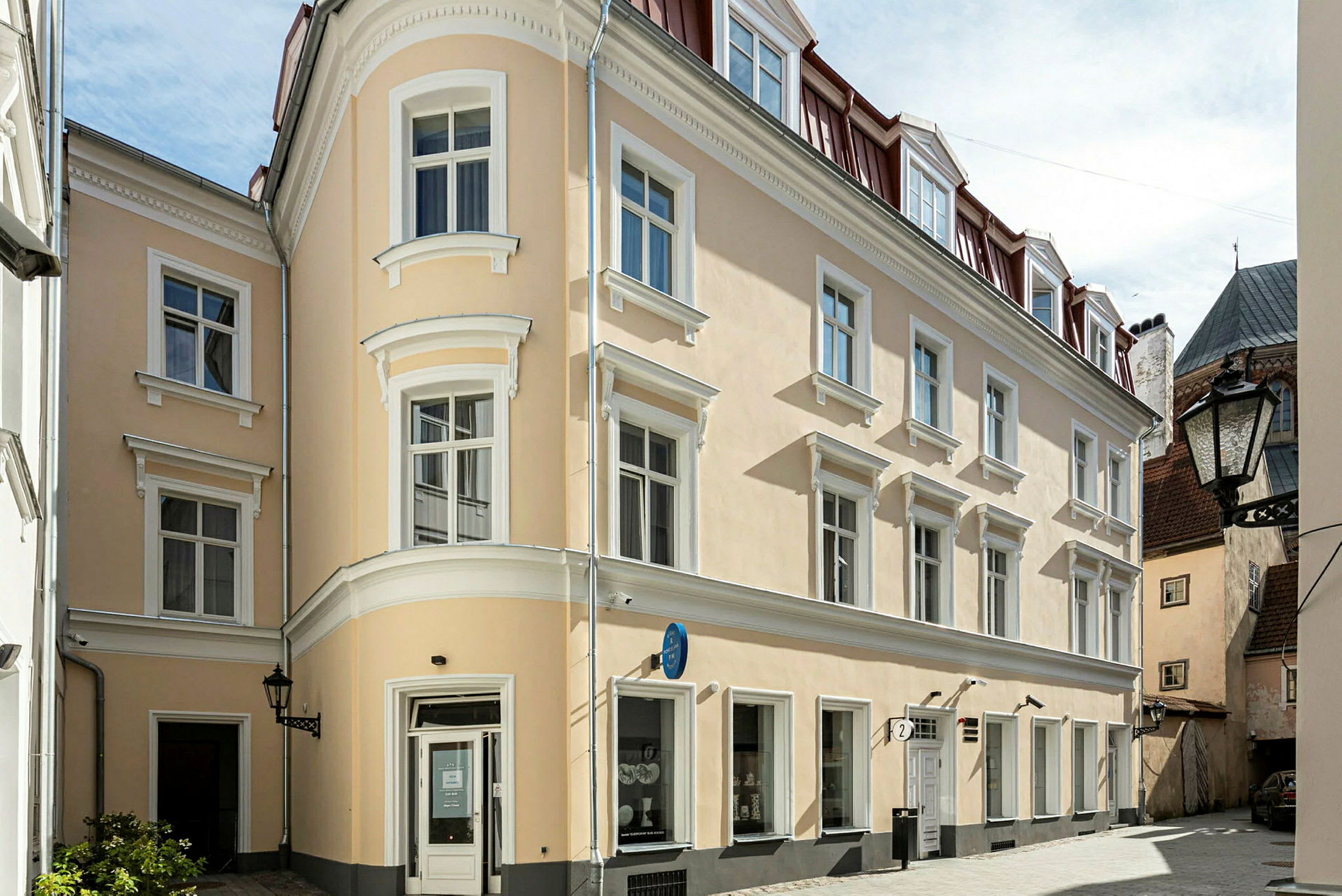 En beige byggnad med vita detaljer och röda tak i ett stadsområde. (AI-genererad text)