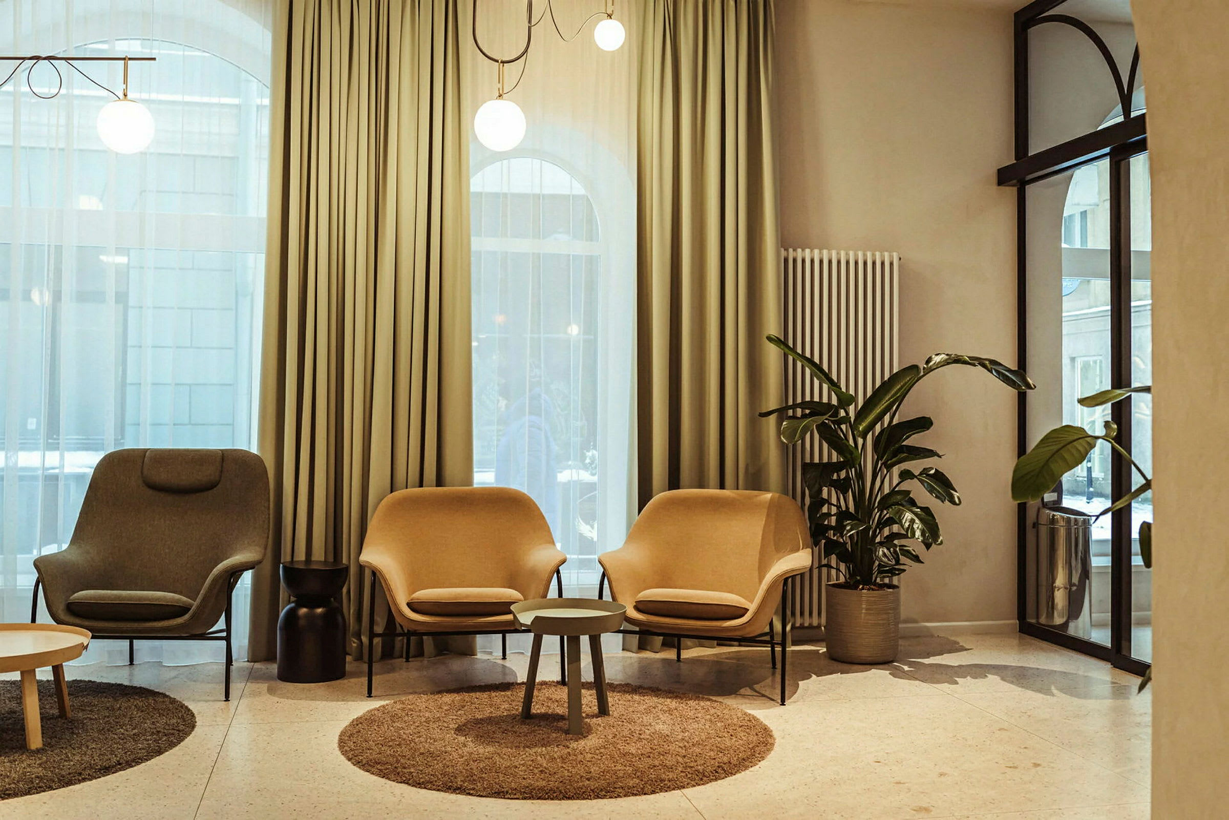 Ett loungeområde med fåtöljer och bord, omgiven av stilrena gardiner och inredningsdetaljer. (AI-genererad text)
