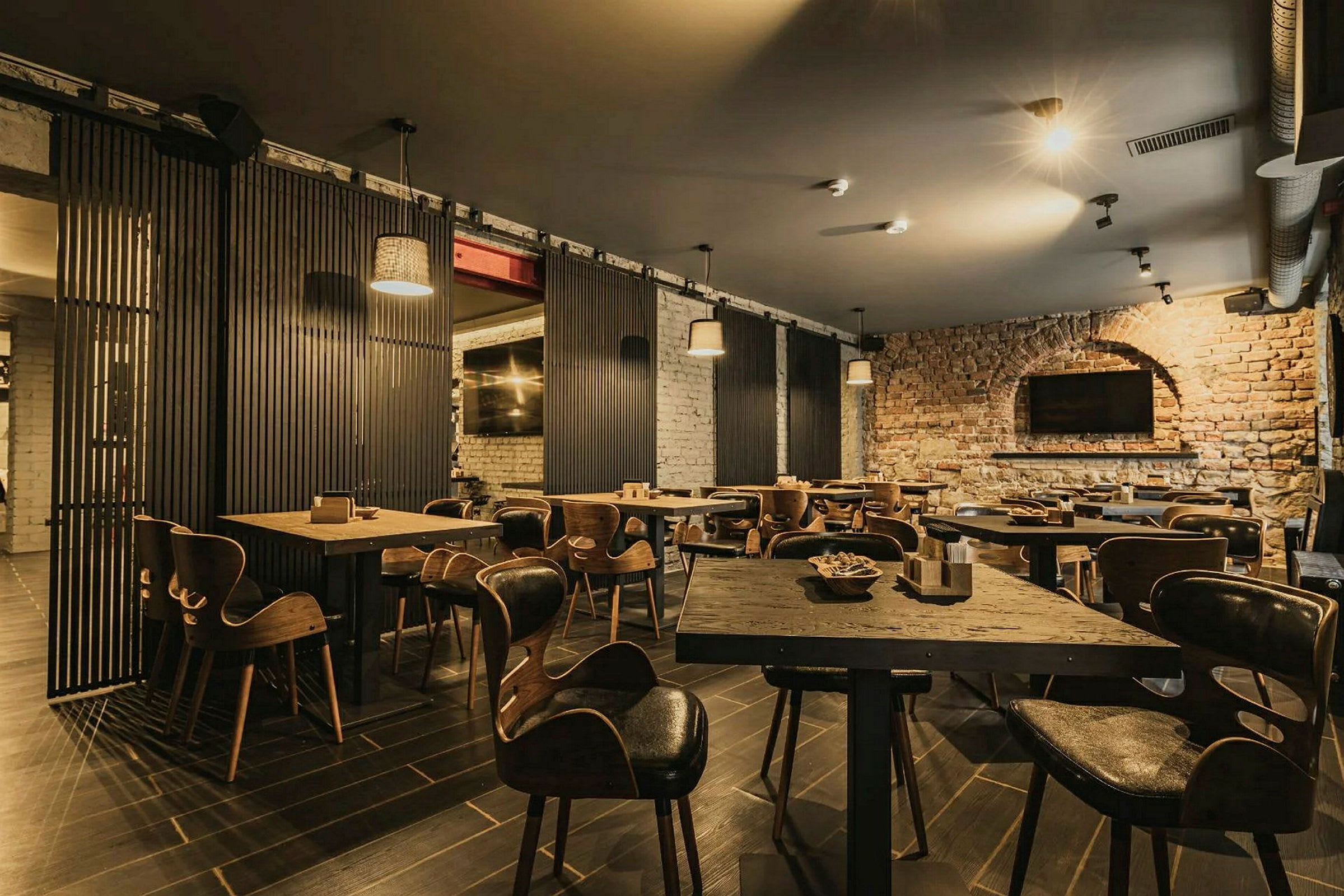 En restaurang med träbord och stolar samt tegelväggar. (AI-genererad text)