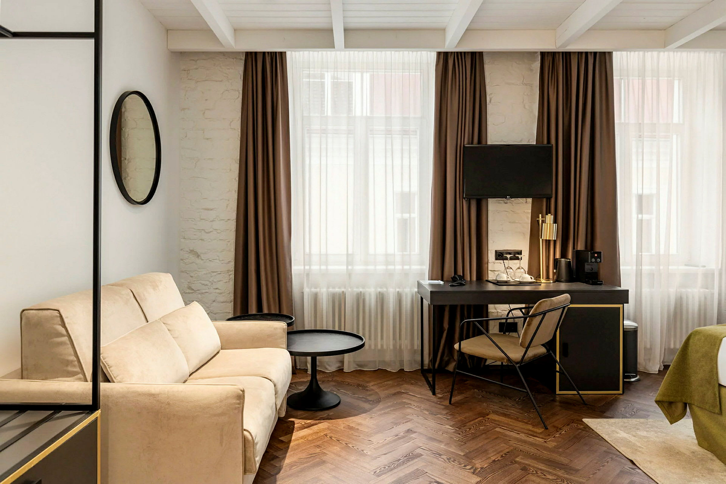 Modernt möblerat hotellrum med soffa, skrivbord och TV. (AI-genererad text)