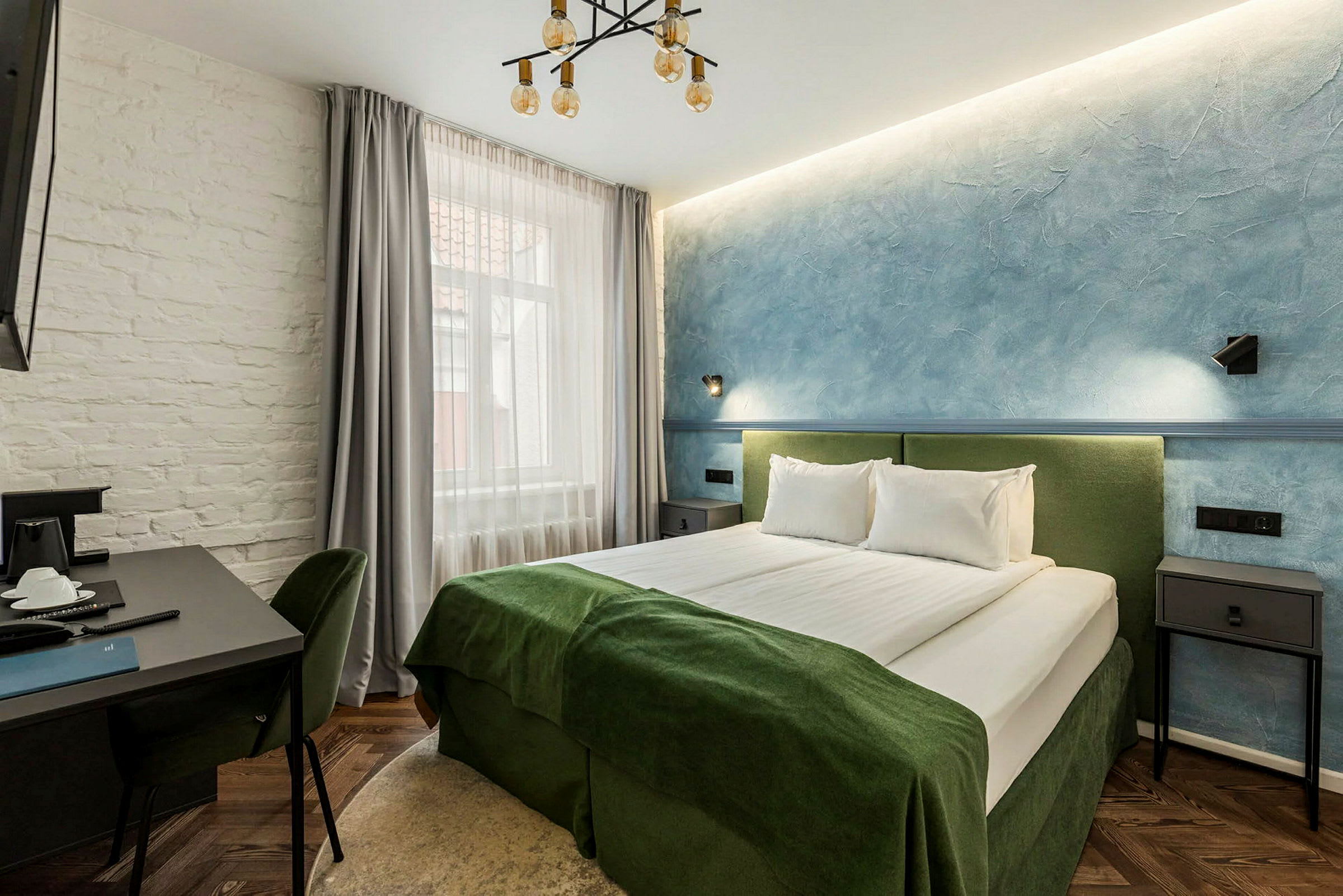 Ett hotellrum med en dubbelsäng, bord och stolar. (AI-genererad text)