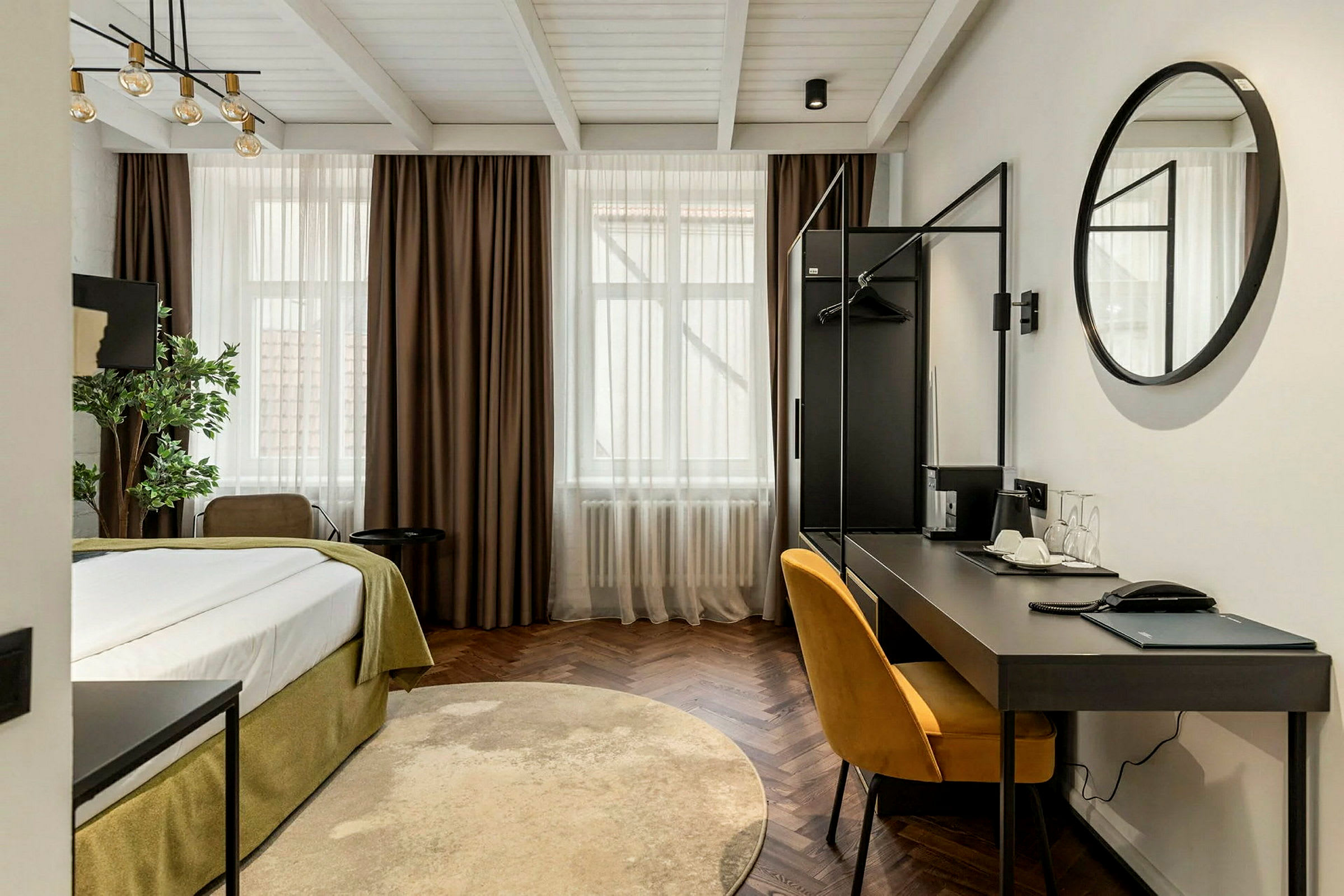 Ett modernt hotellrum med en säng, skrivbord och en gul stol. (AI-genererad text)