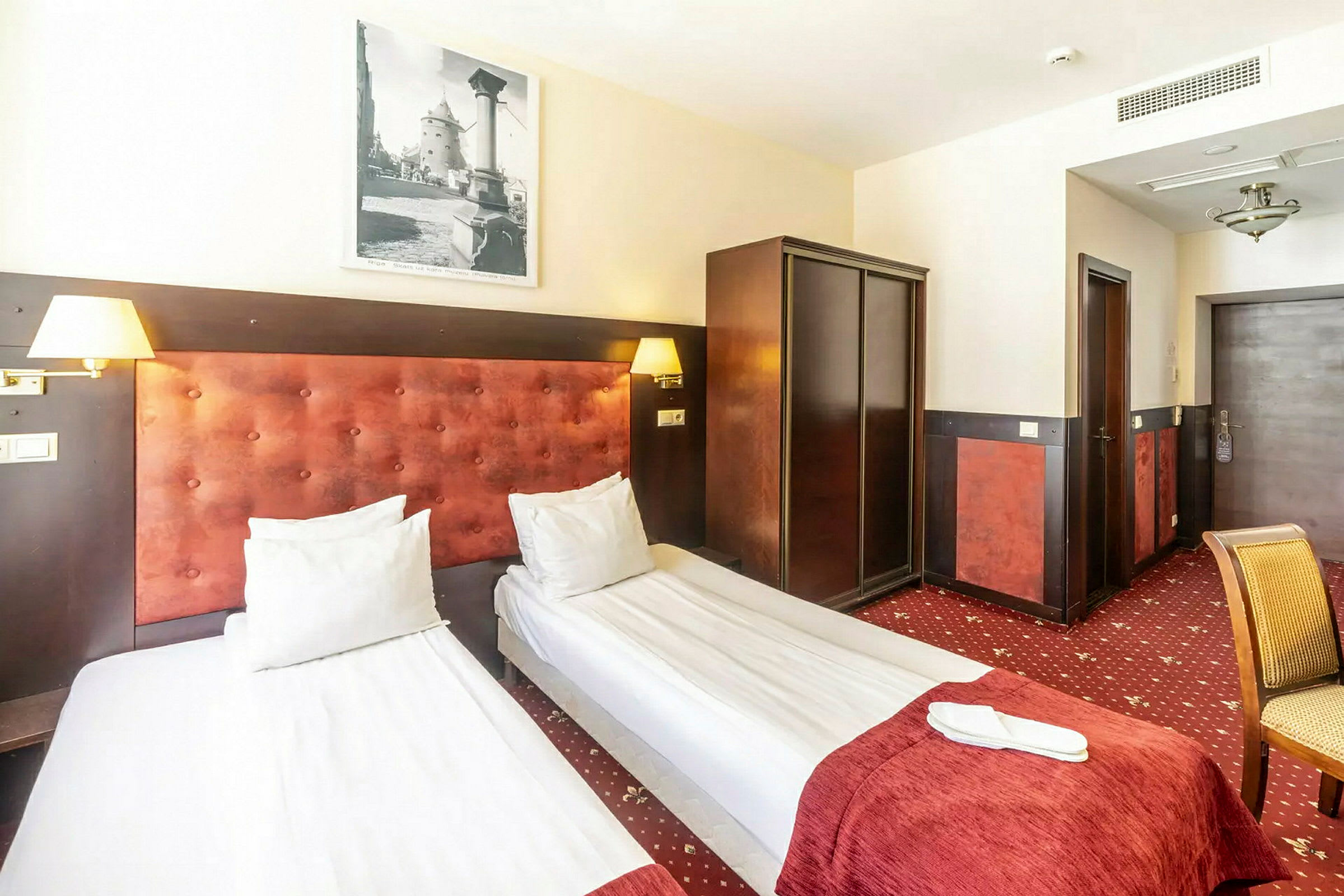 En hotellrum med två enkelsängar, en garderob och stol. (AI-genererad text)