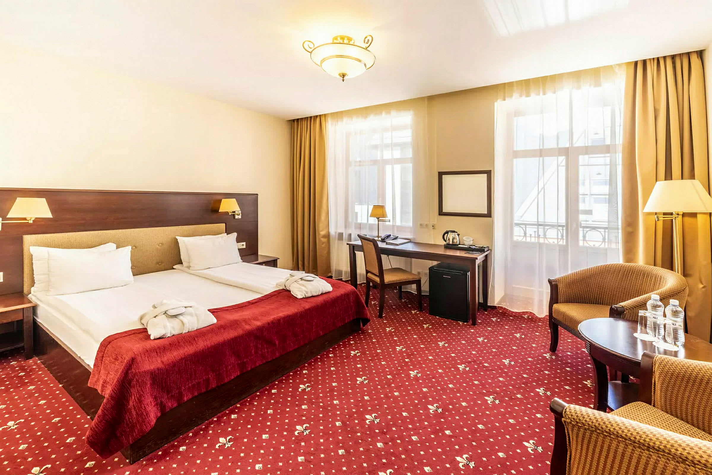 Ett hotellrum med två enkelsängar, ett skrivbord och en sittgrupp. (AI-genererad text)