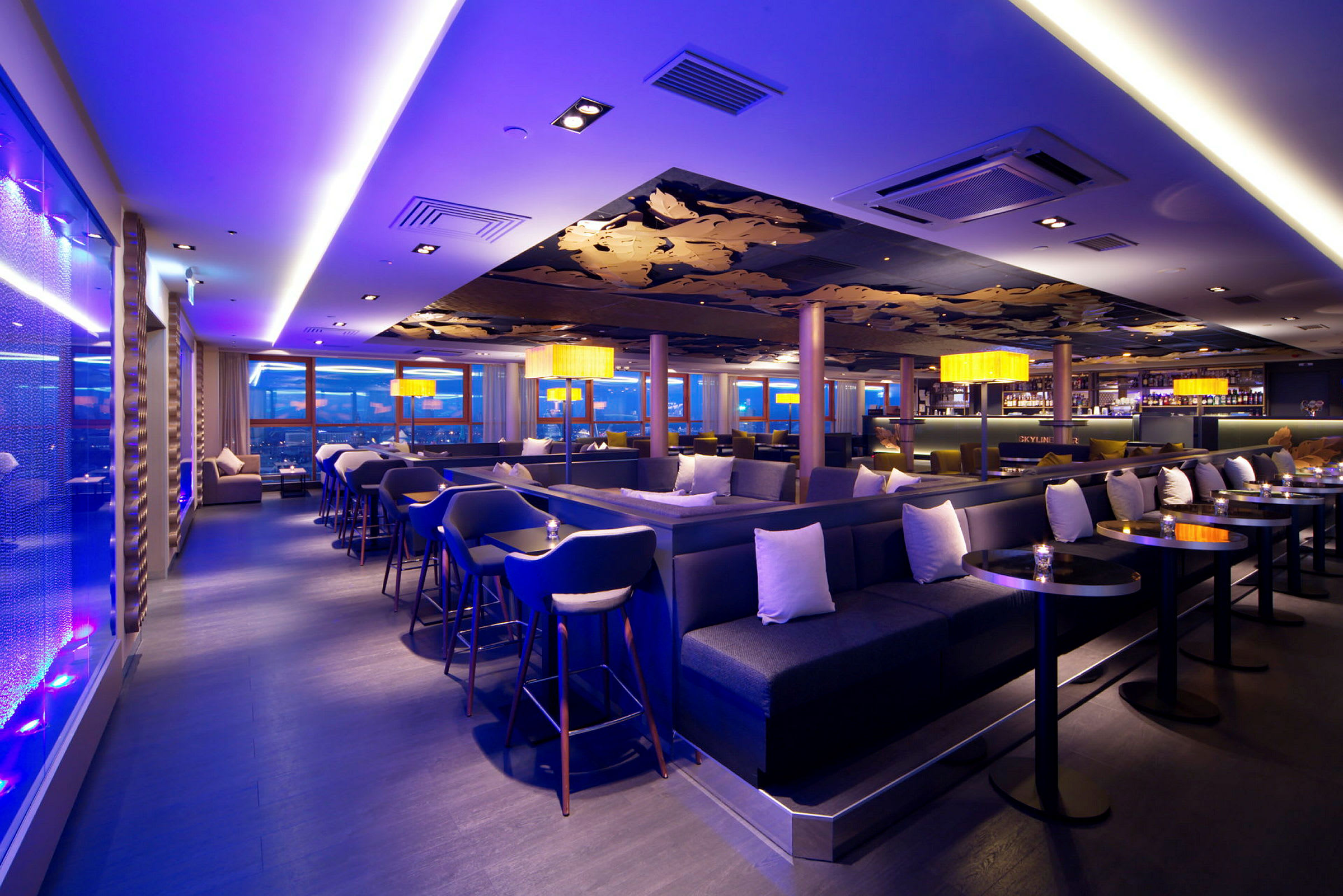 En elegant lounge- och barområde med moderna möbler, stämningsfull belysning och stora panoramafönster. (AI-genererad text)