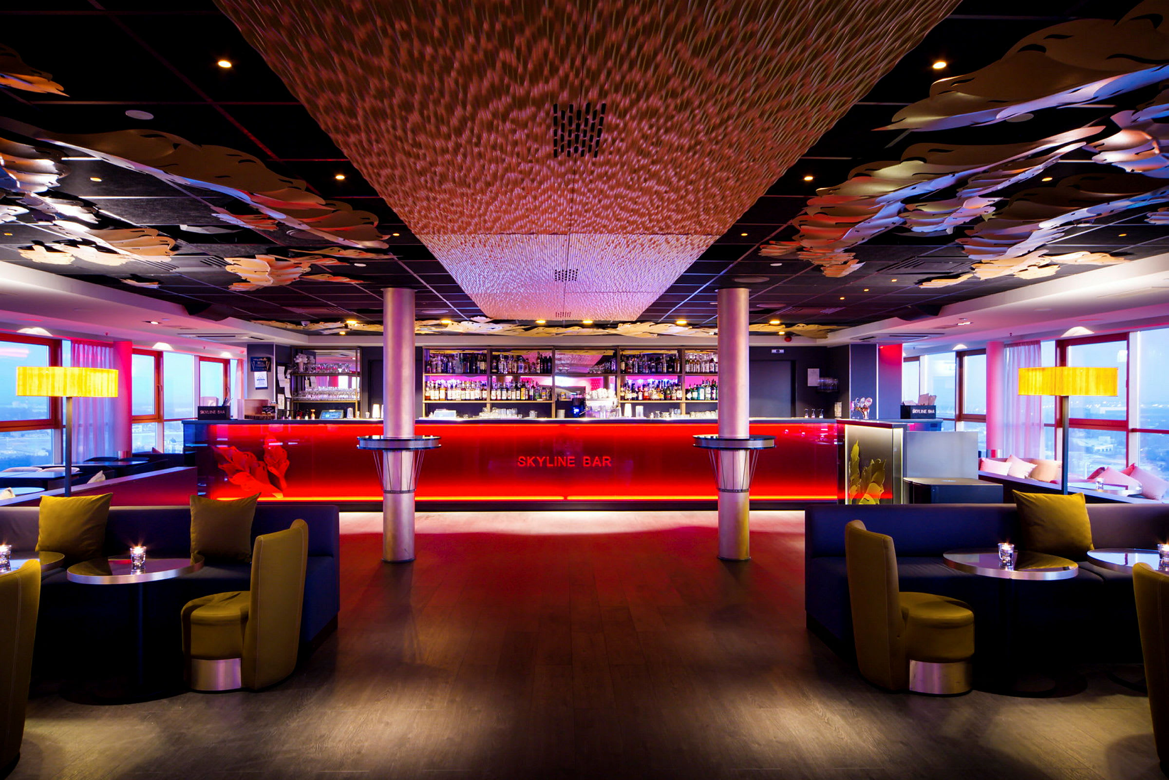 En elegant bar med röd belysning, mörka möbler och dekorerade tak. (AI-genererad text)