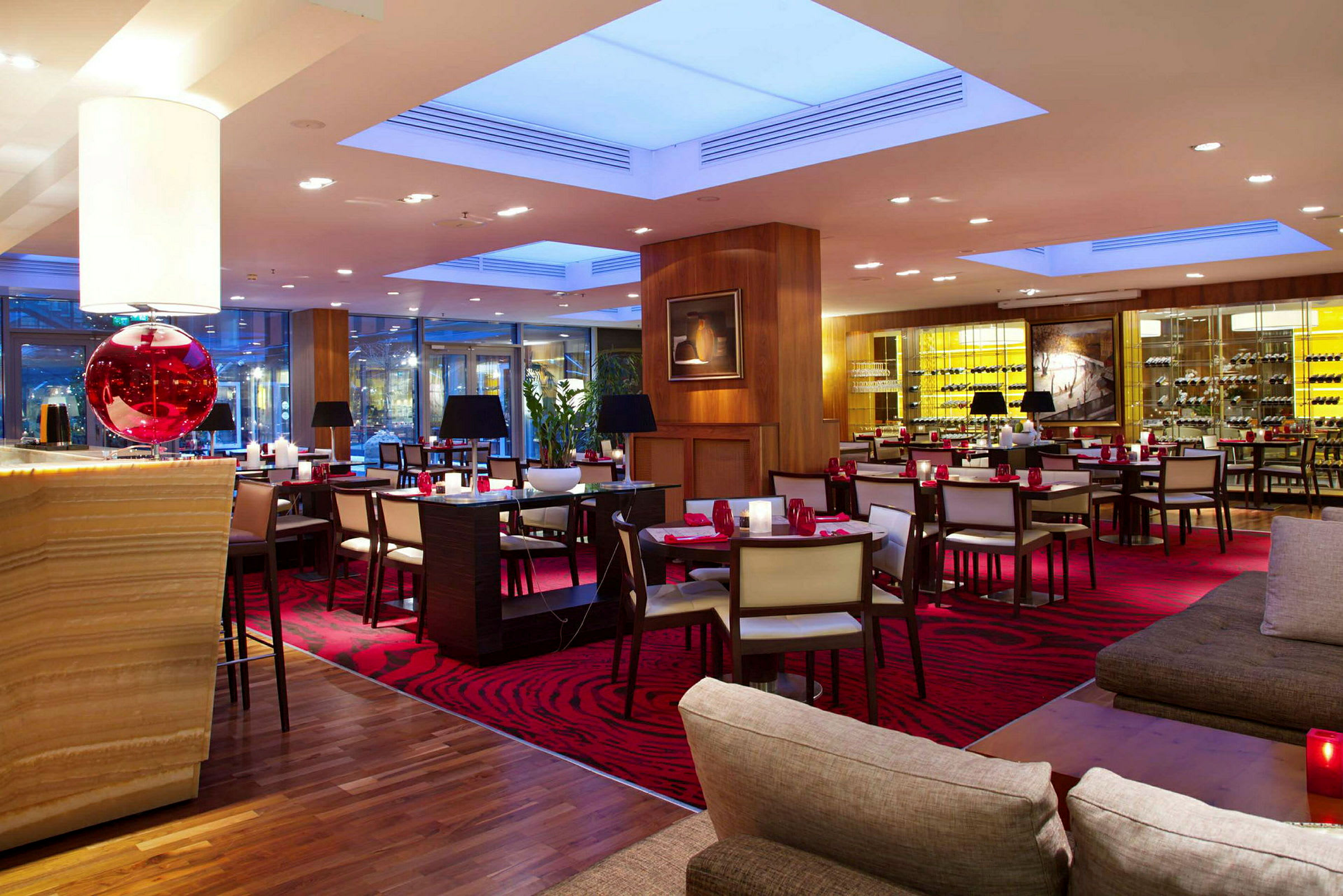 En elegant restaurang med röda mattor och modern inredning, med bord, stolar och en avslappnad atmosfär. (AI-genererad text)