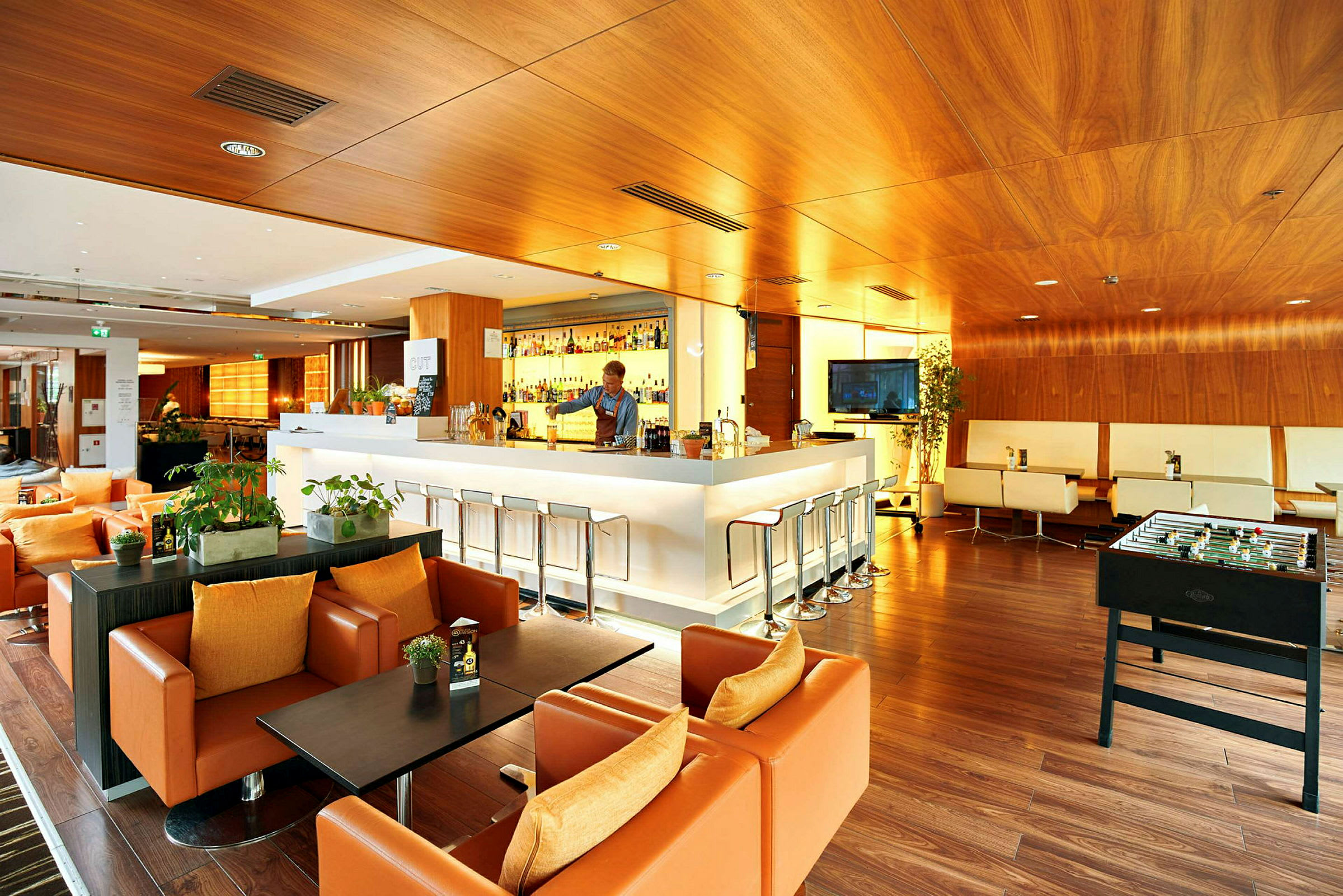 En modern lounge med en bar, sittgrupper och en fotbollsspel. (AI-genererad text)