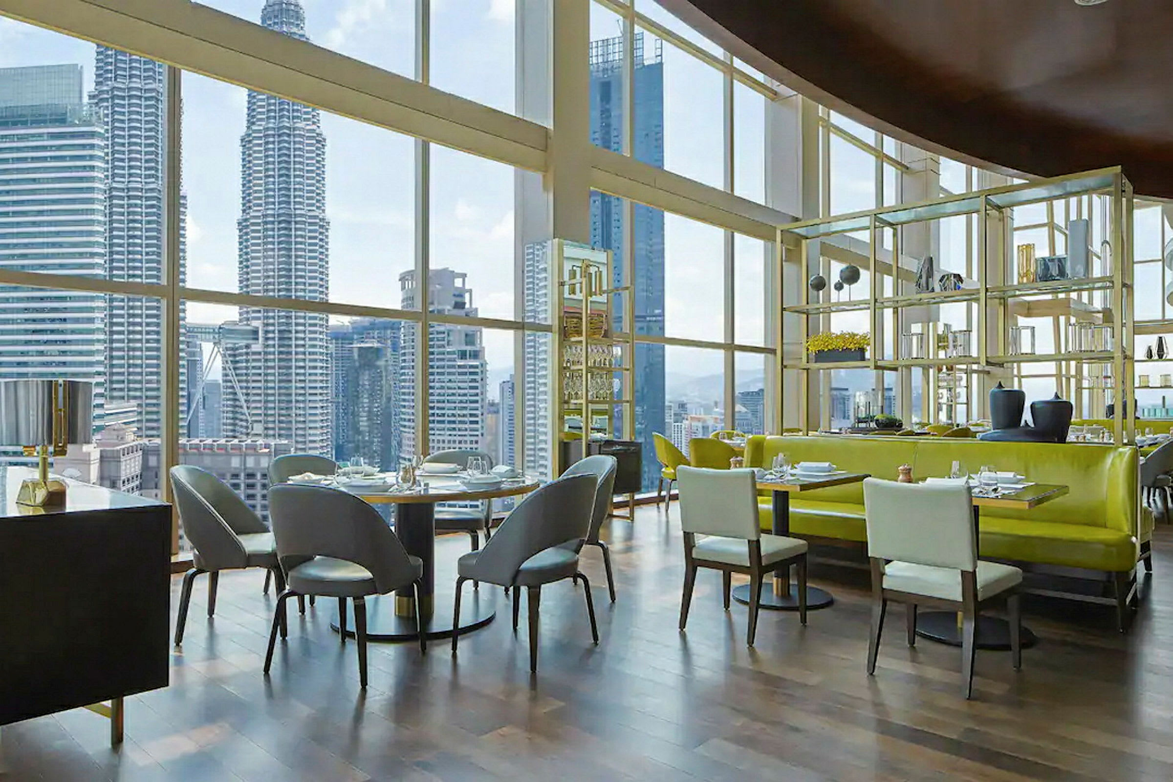 Interiör av en modern restaurang med stora fönster som ger utsikt över en stadsskyline inklusive höghus. (AI-genererad text)