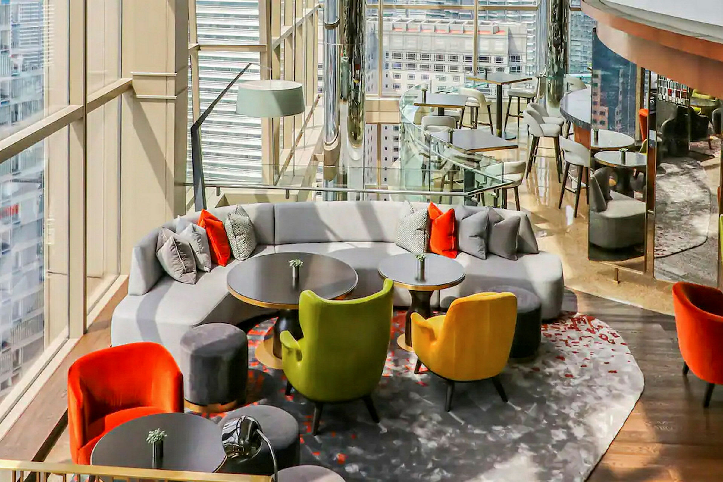 En elegant lounge med moderna möbler, kuddar och utsikt genom stora glasfönster. (AI-genererad text)