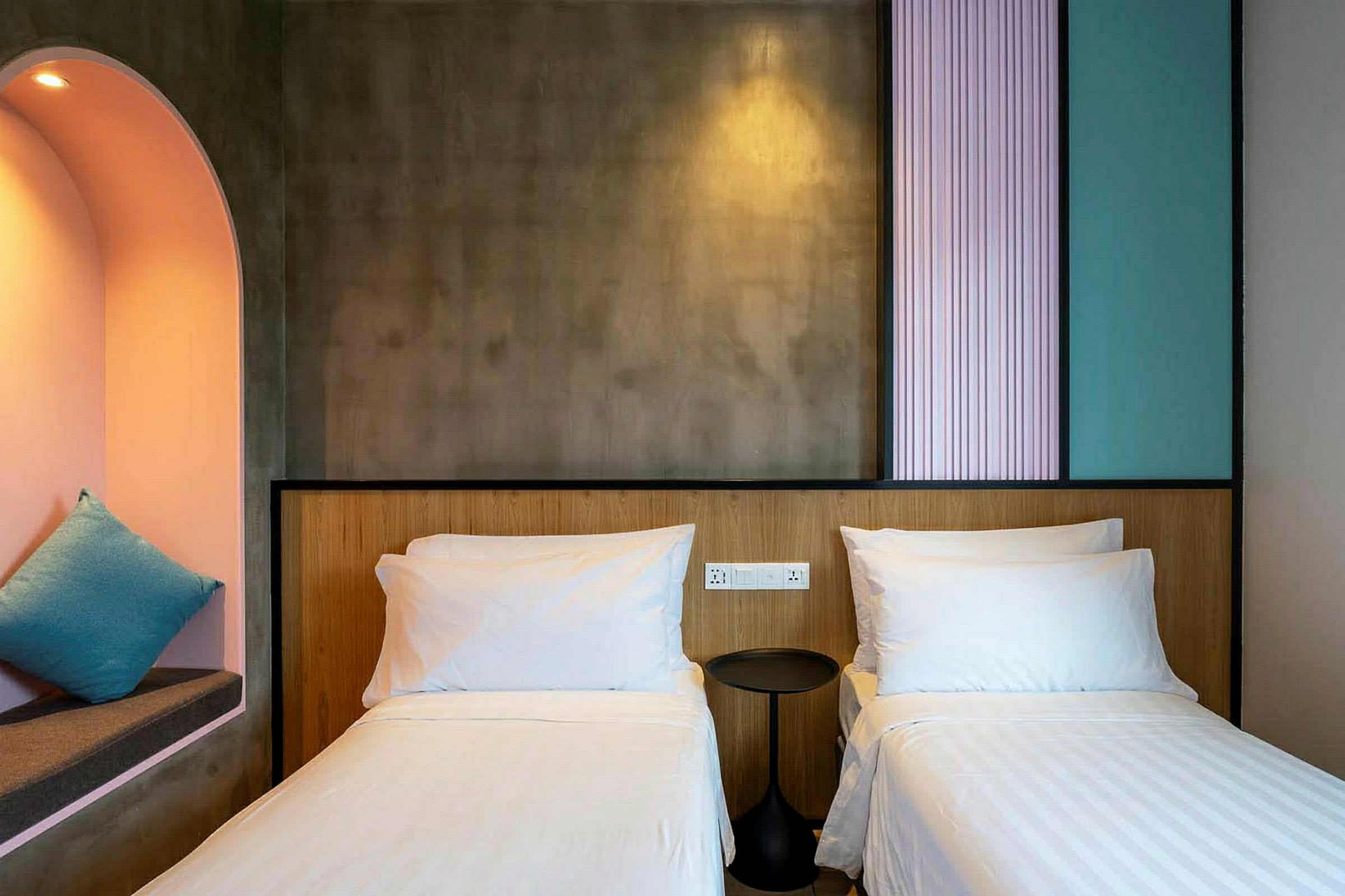 Ett hotellrum med två enkelsängar, en liten rund nattduksbord, och en inbyggd alkova med en kudde. (AI-genererad text)