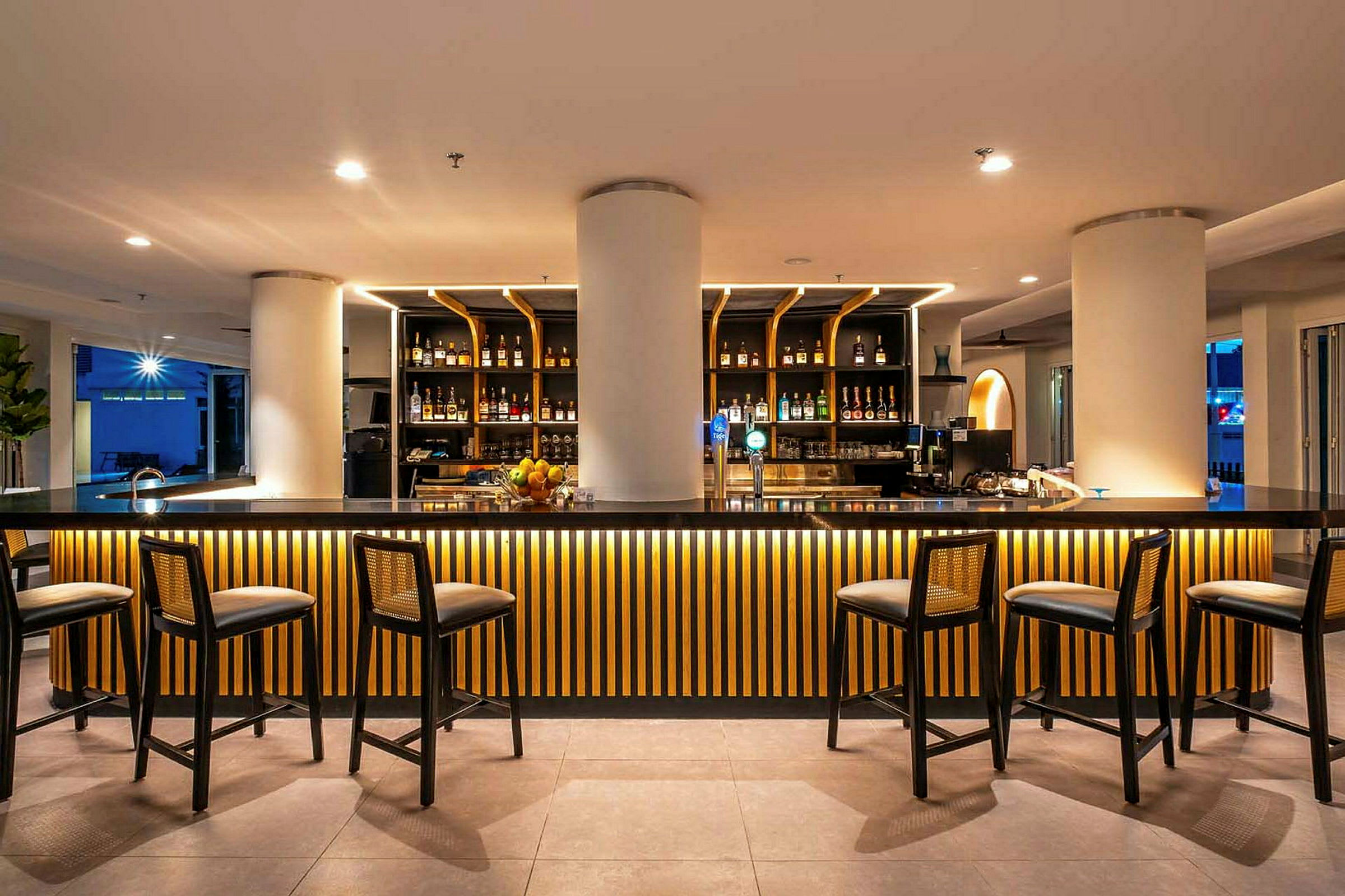 En bild av en elegant bar med högstolar och en upplyst bardisk dekorerad med träpaneler. (AI-genererad text)