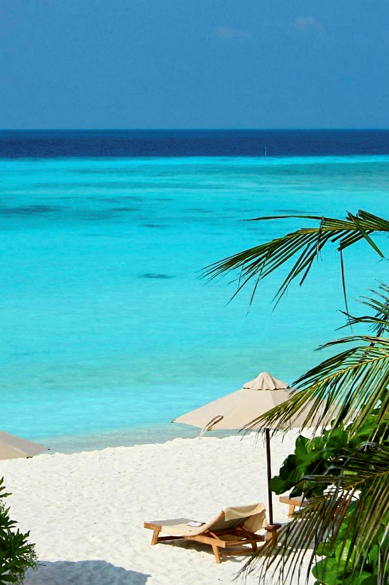 Vit sandstrand med parasoller, solstolar och utsikt över det turkosa havet. (AI-genererad text)