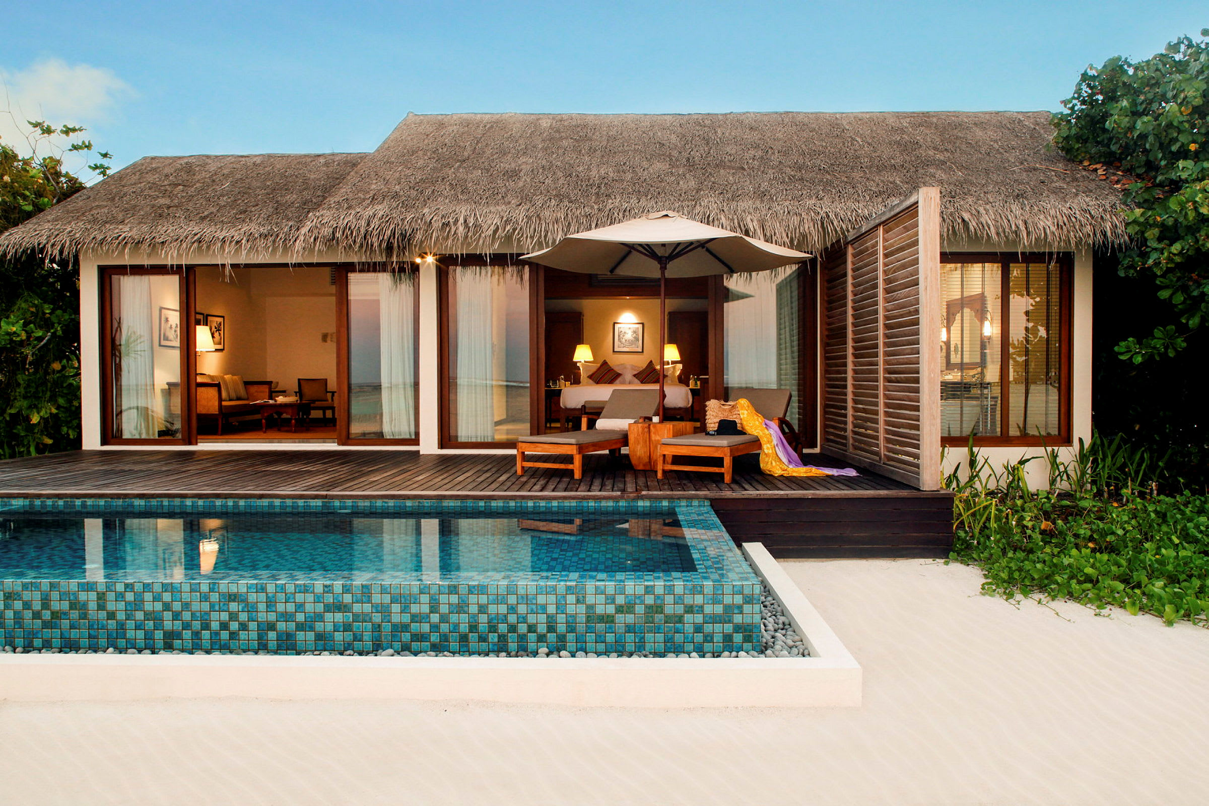 En strandvilla med privat pool och sittmöbler på en träterrass. (AI-genererad text)