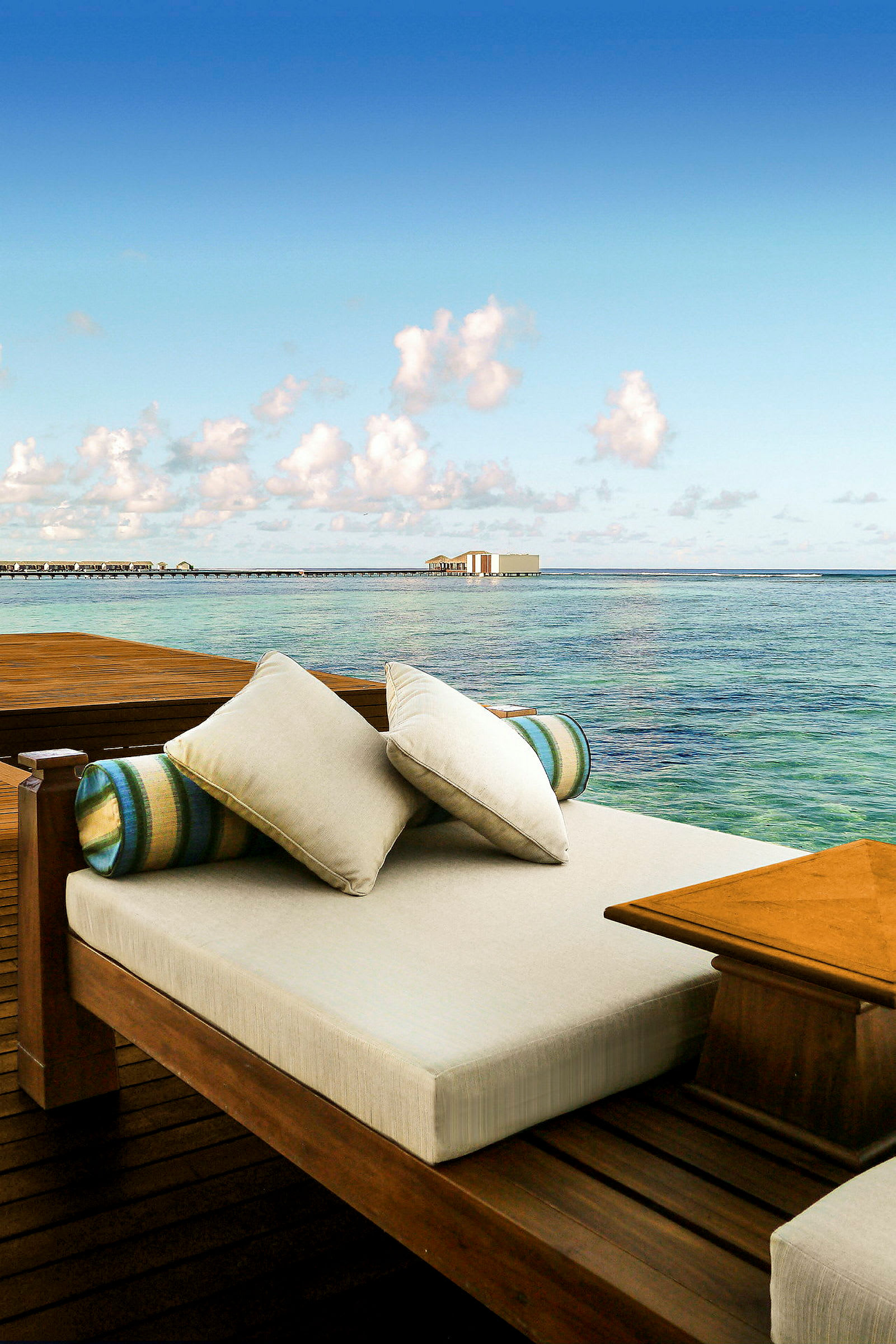 En lounge med kuddar intill havet och en vadplattform. (AI-genererad text)