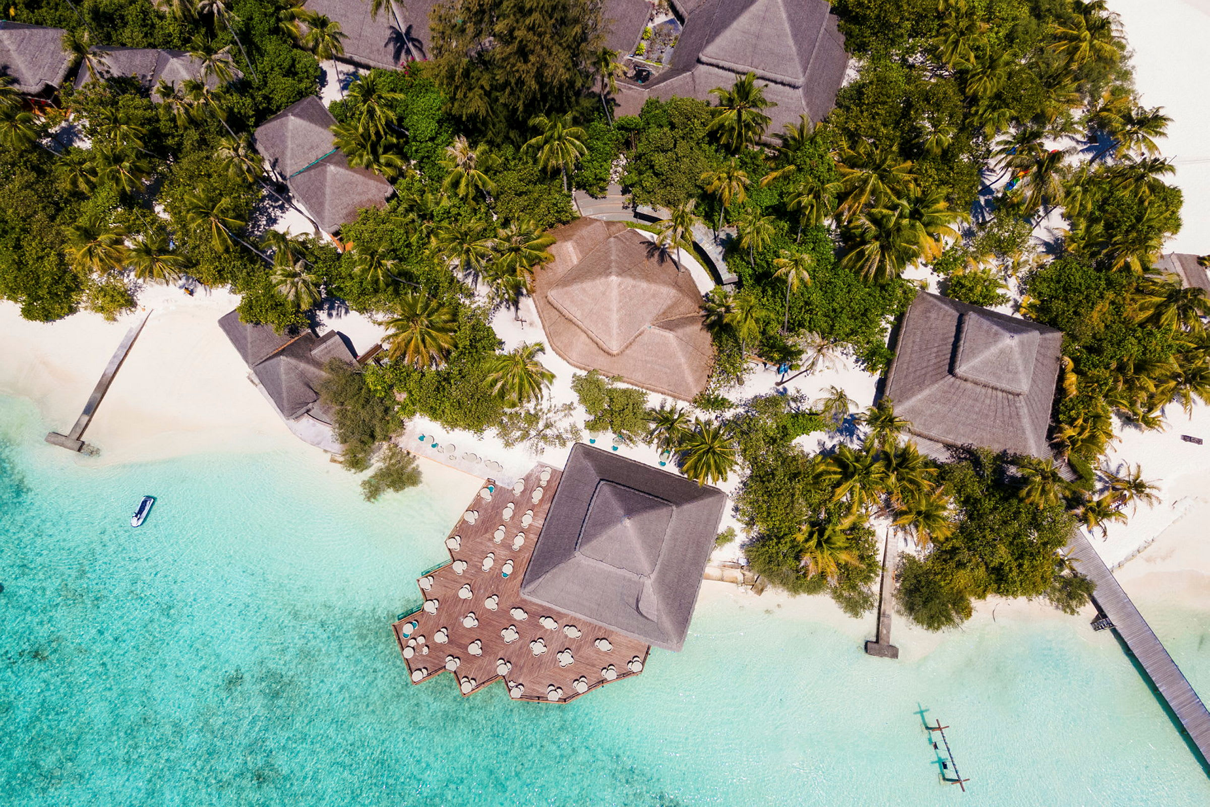 Flygfoto av tropisk resort med bungalower omgivna av grönska och klarblått vatten. (AI-genererad text)