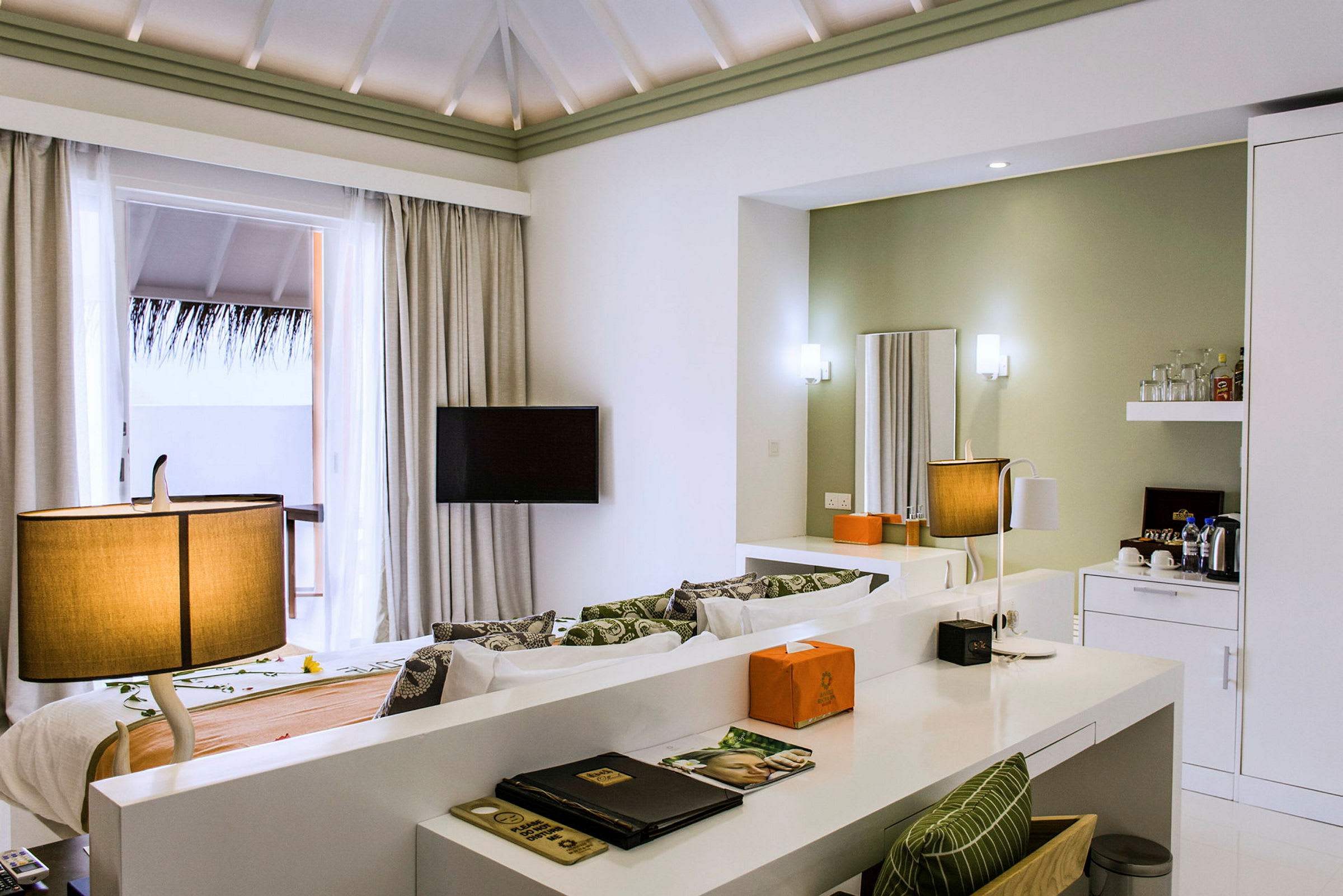 Ett hotellrum med modern inredning inklusive en säng, skrivbord, TV och en balkong med utsikt. (AI-genererad text)